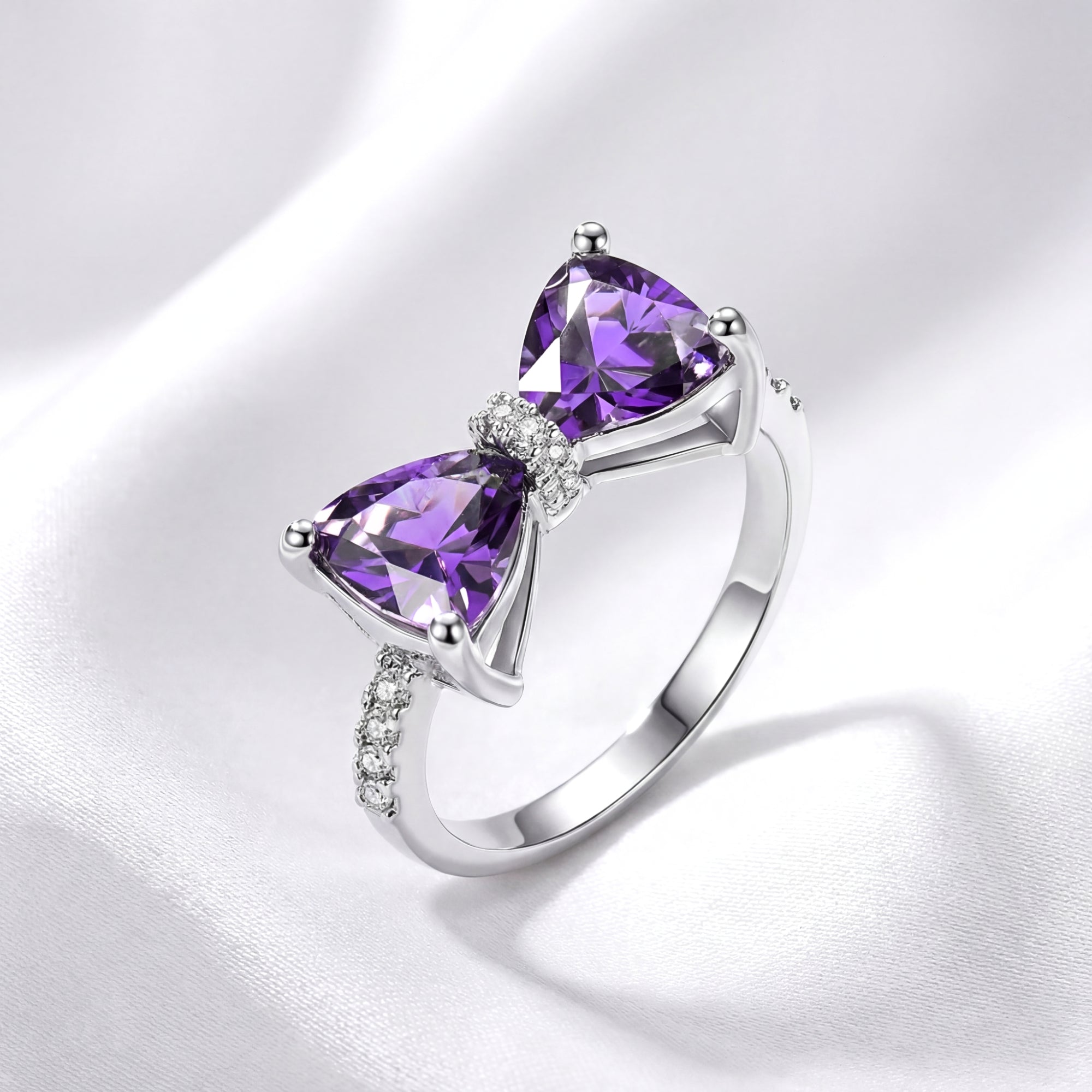 Angled view of the trillion-cut simulated amethyst bow ring in S925 sterling silver on white silk.