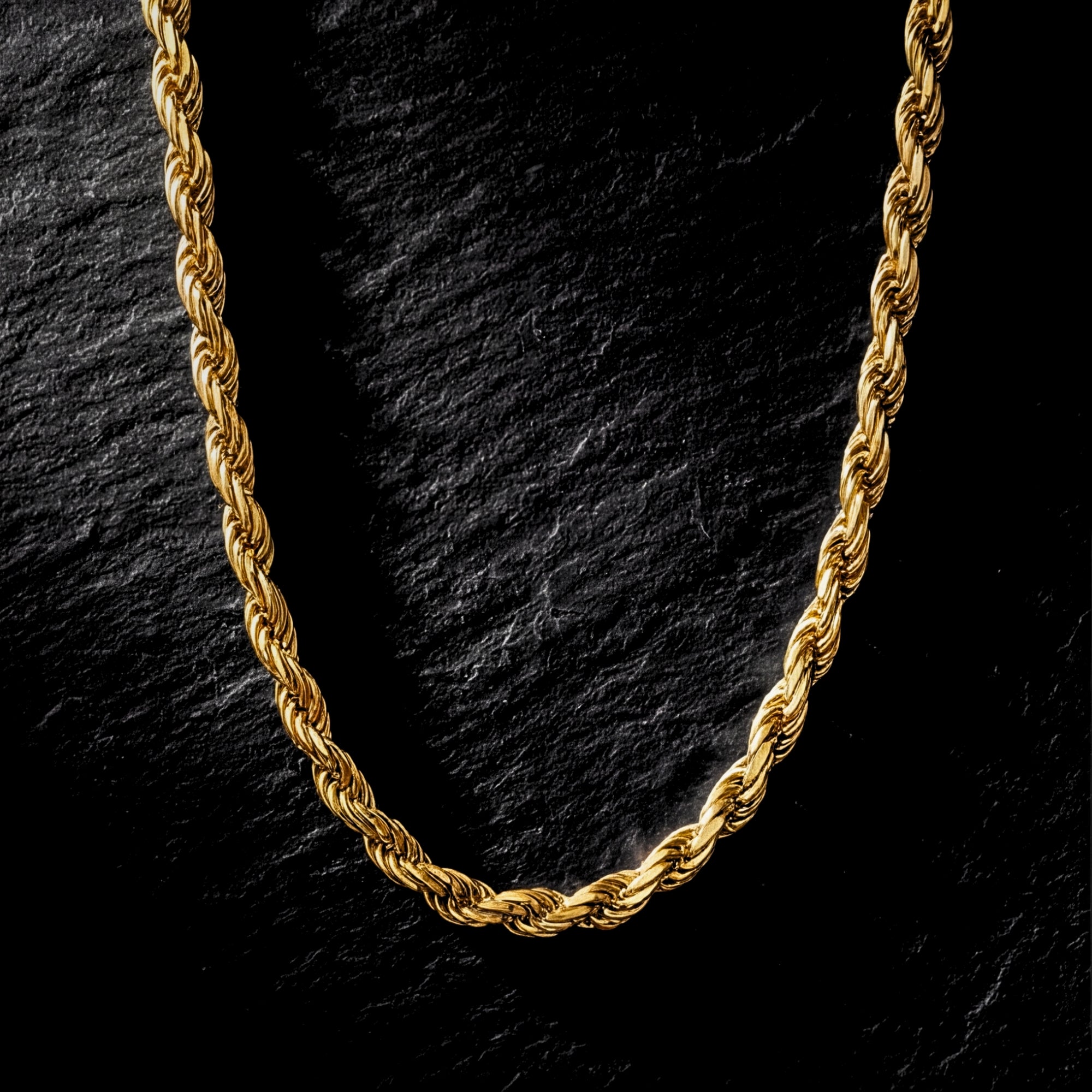 4mm gold rope chain in stainless steel displayed on a dark textured stone background.