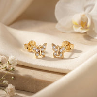 Gold moissanite butterfly studs on silk with flowers.
