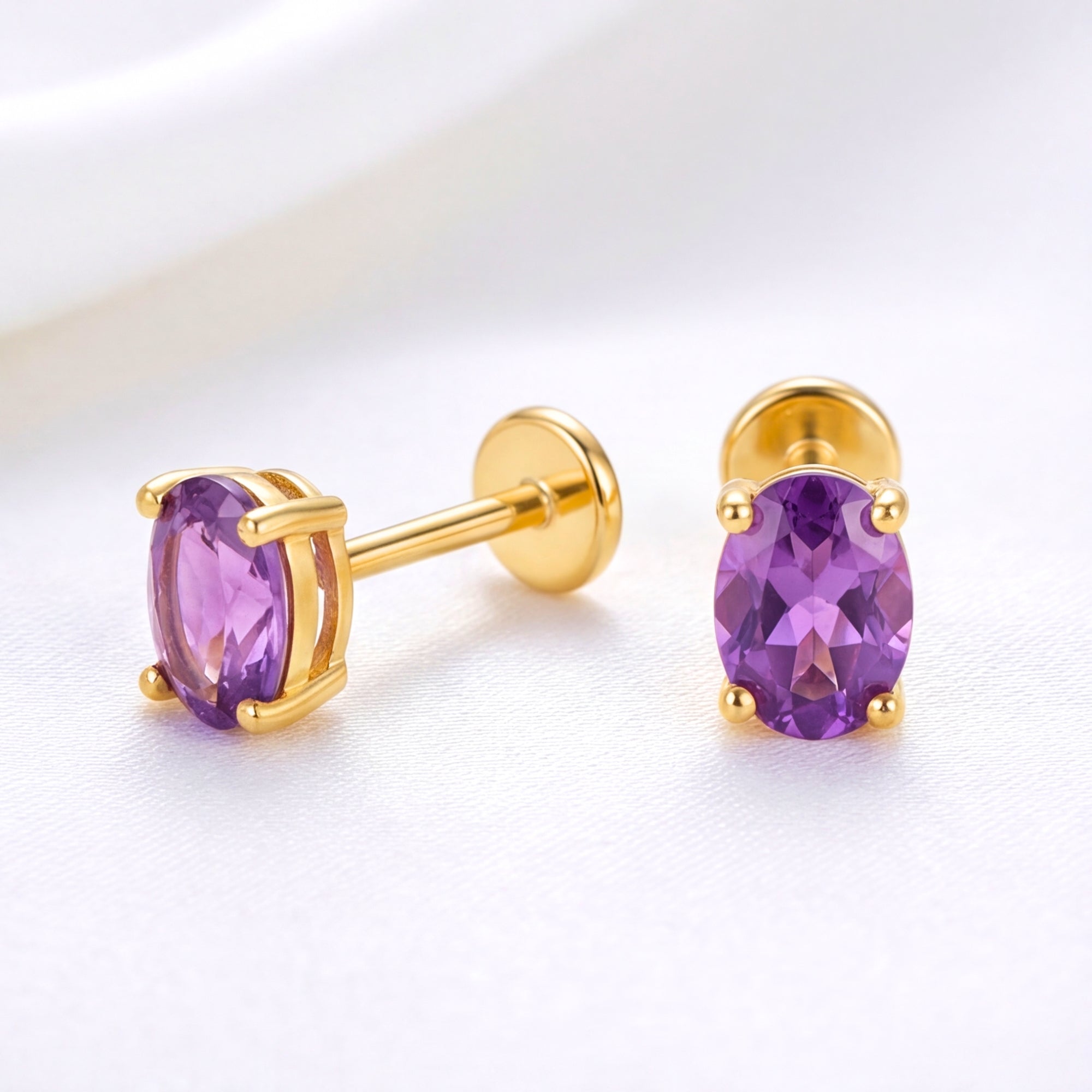 Oval simulated amethyst stud earrings in 18K gold vermeil with flat back posts on a white silk background.