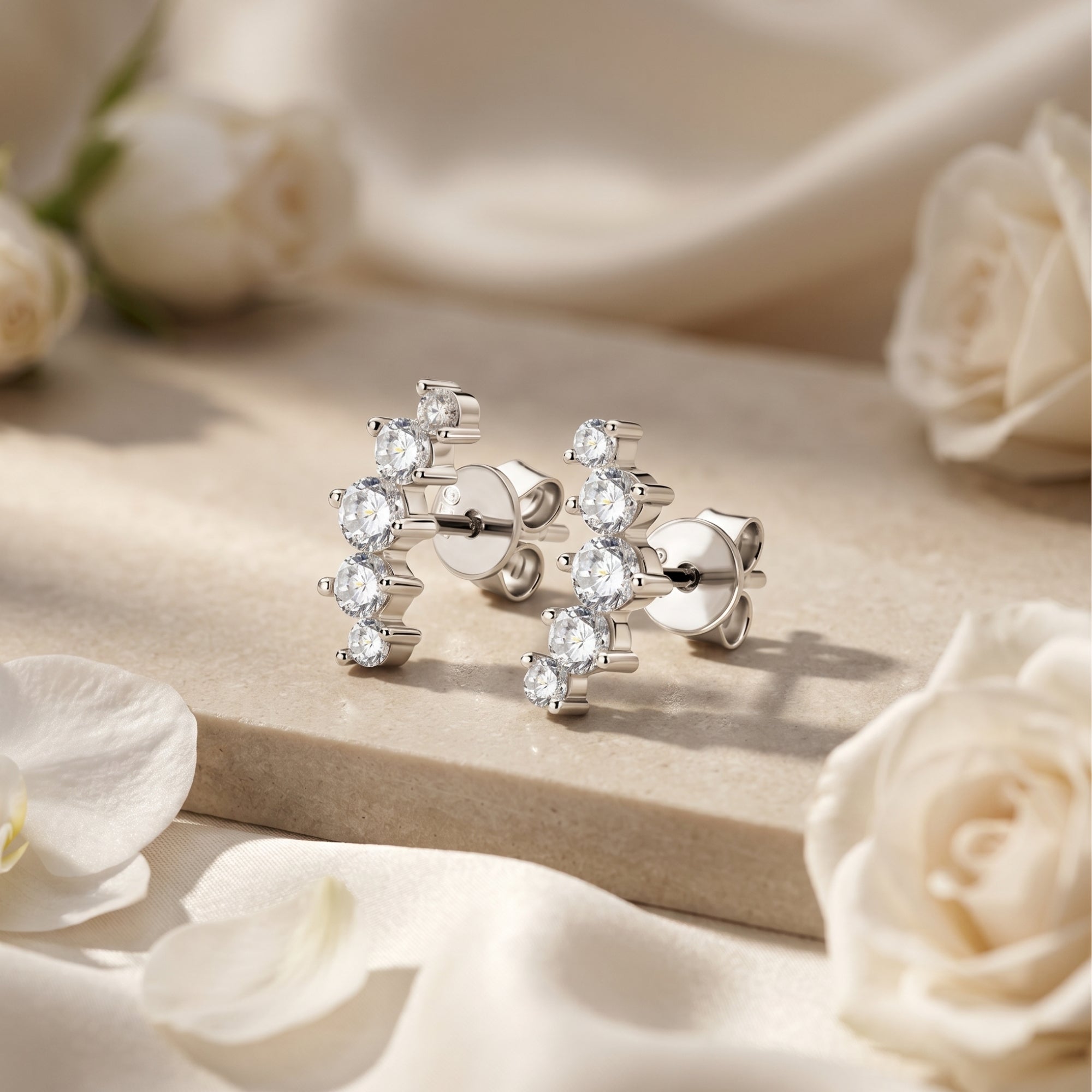 Valeriola silver moissanite climber earrings on stone with white roses.
