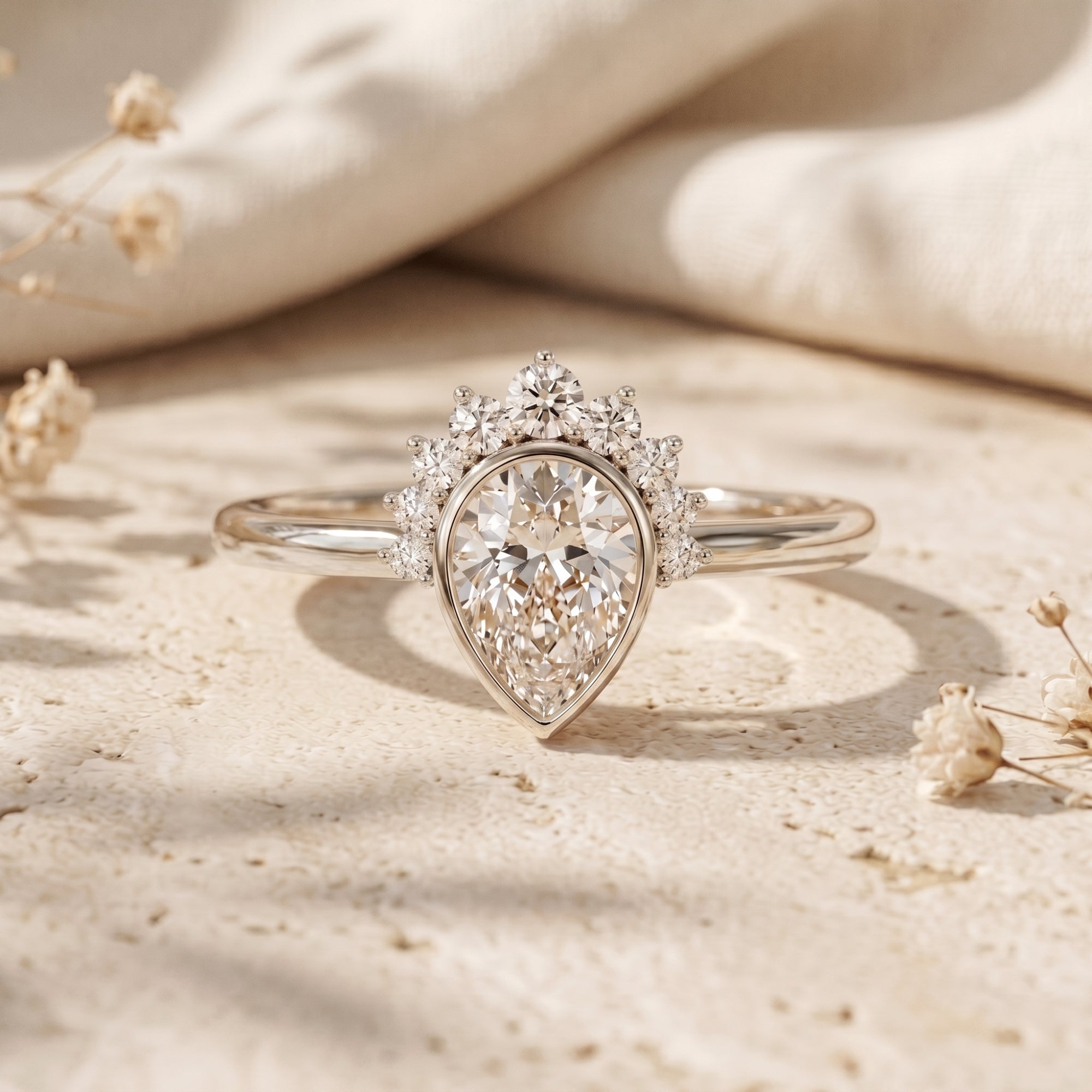 Silver pear-cut moissanite promise ring with tiara accents on a stone surface.