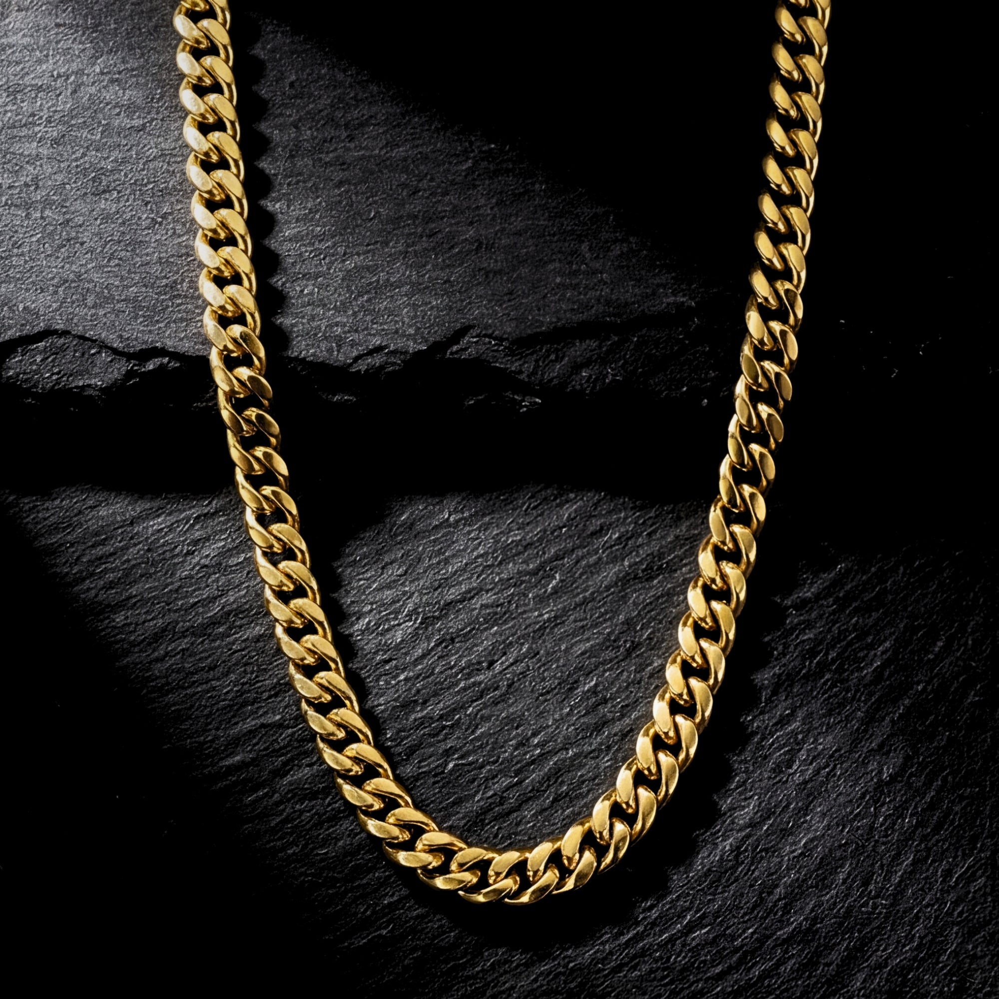 8mm gold Cuban chain in stainless steel from the Origin Collection on a dark stone background.
