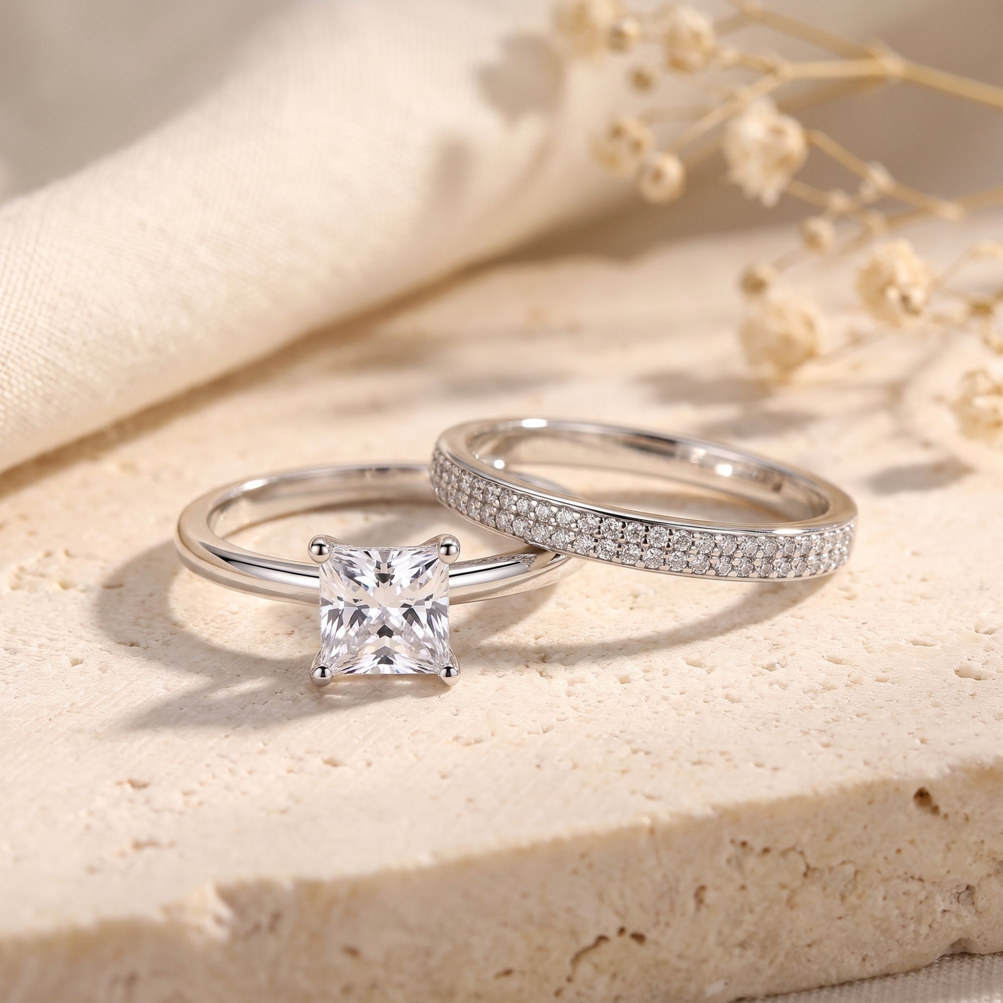 Sterling silver princess cut simulated diamond ring set on stone with dried flowers.