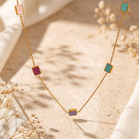 Gold-tone station necklace with pastel and jewel-toned enamel square tiles on a delicate link chain.