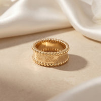 The Vowbound Ring in 18K gold vermeil with beaded edges and script engraving on a soft fabric background.