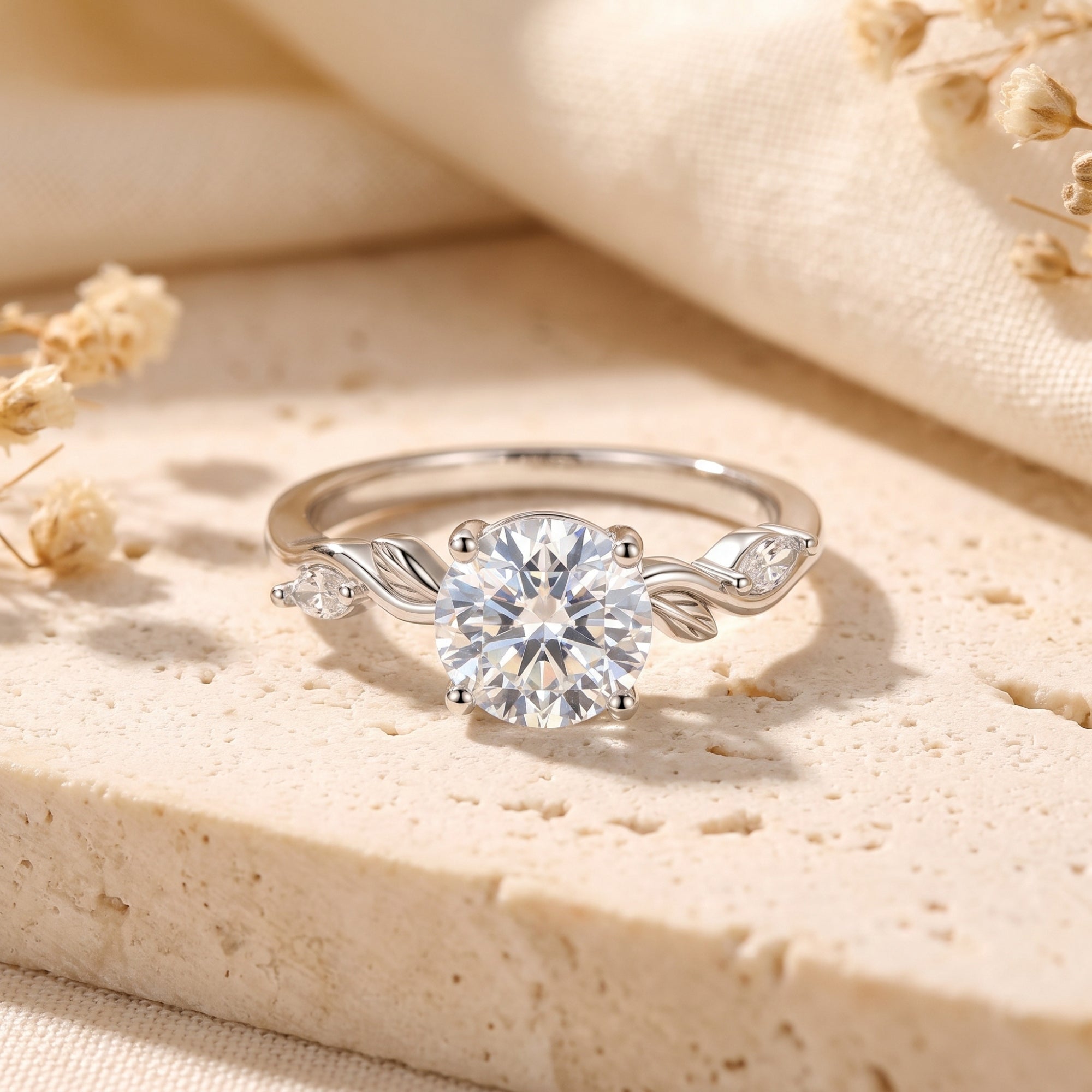 Sterling silver round-cut simulated diamond ring with leaf motif on a textured stone background.