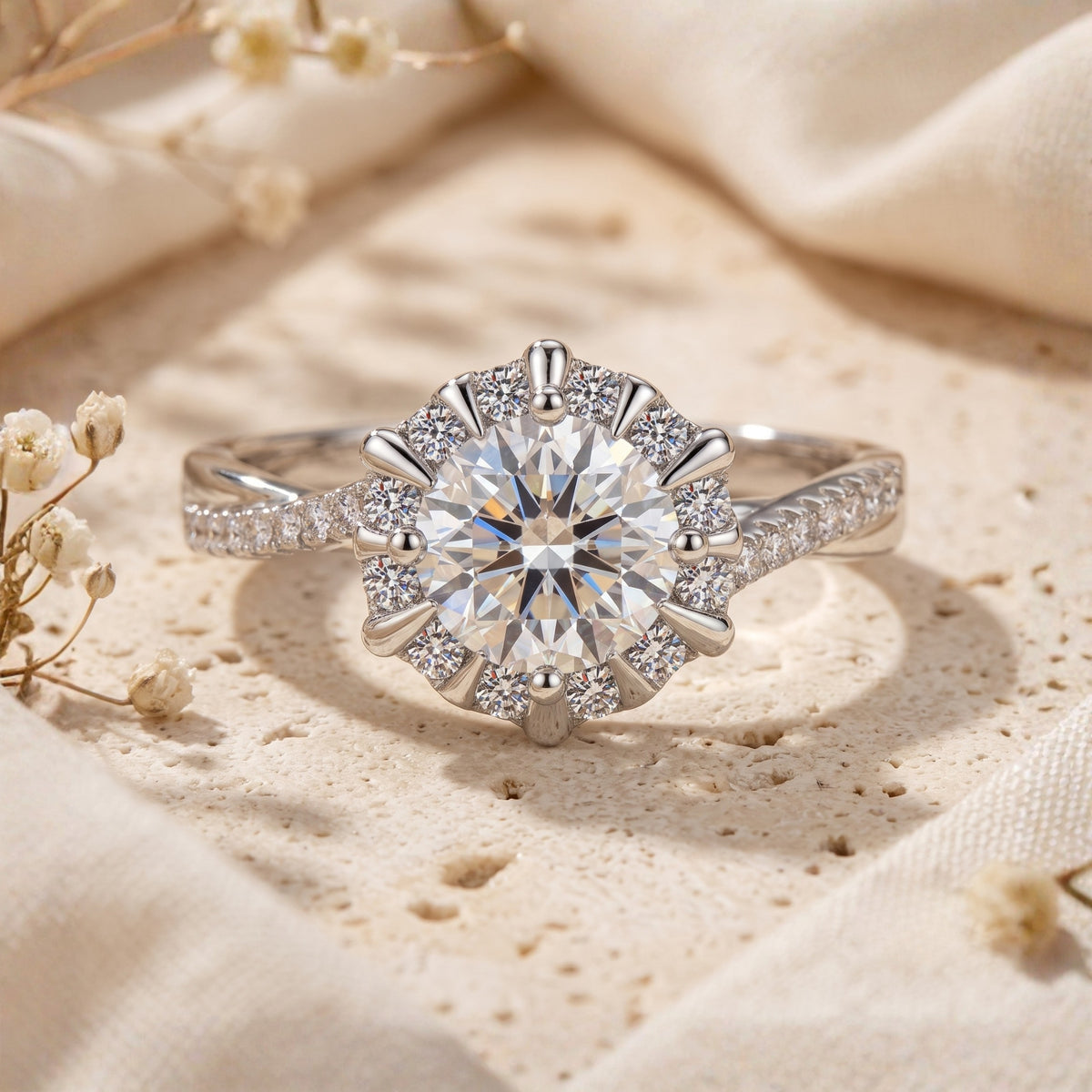 Close-up of a silver ring with a round center stone, sunburst halo, and twisted pavé band.