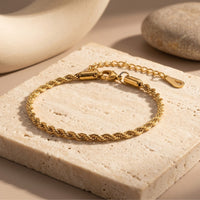 Gold 18K plated stainless steel rope bracelet on a stone slab lifestyle background.