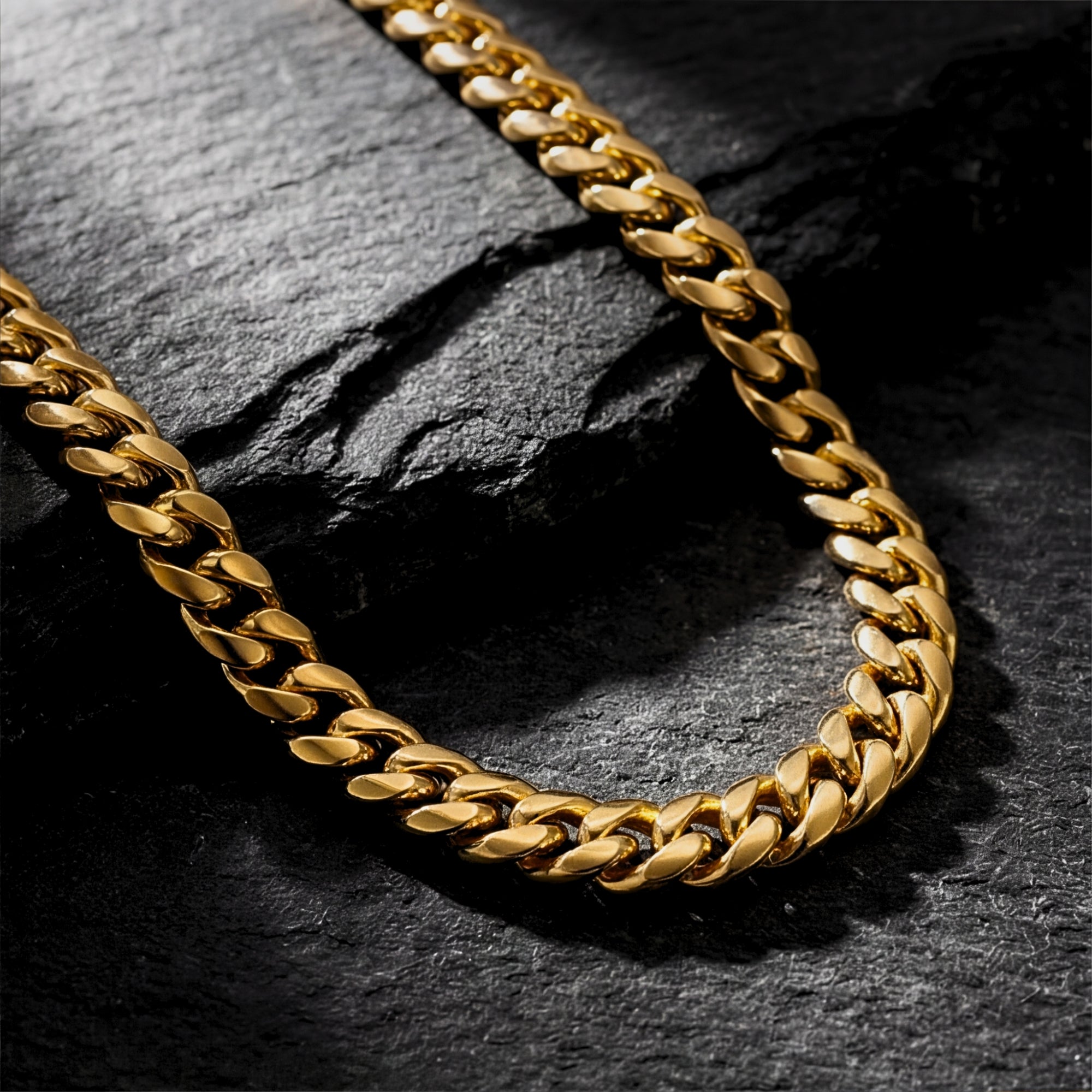 Close-up of 8mm gold ion-bonded stainless steel links on a Cuban chain necklace over dark stone.