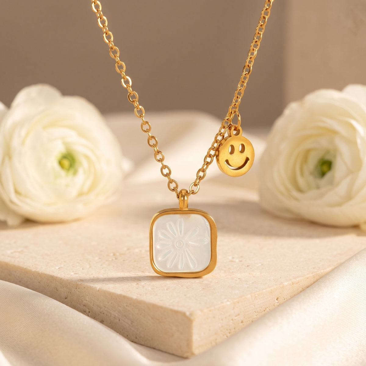 Close-up of the gold-tone necklace with a white shell daisy pendant and smiley-face charm.