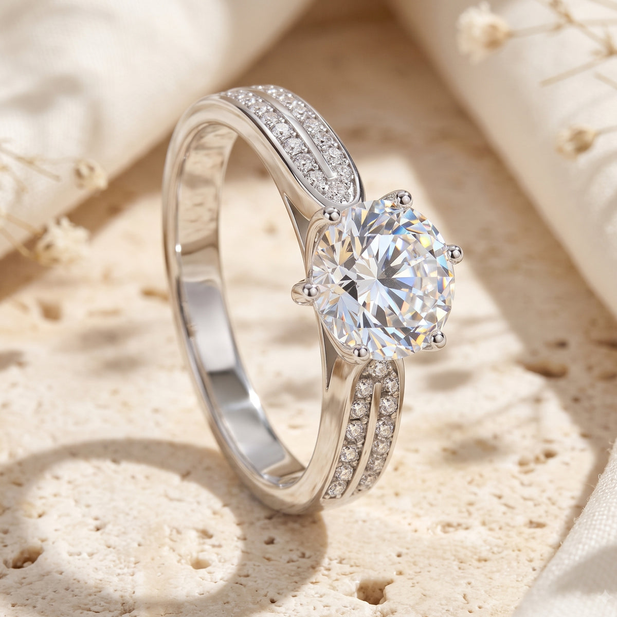 Silver split-shank ring with a round clear center stone in a six-prong setting on a textured stone surface.