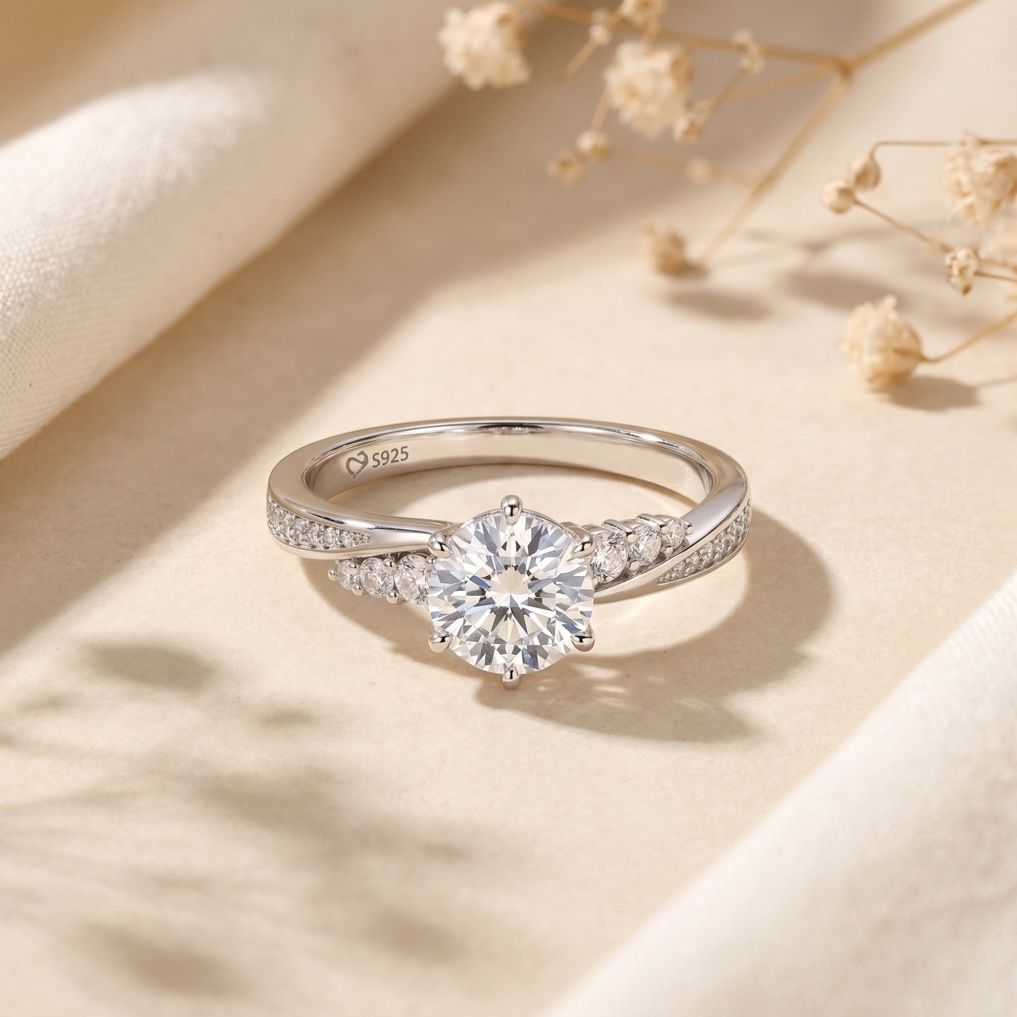 Nicolette 2ct round moissanite ring in sterling silver on a neutral lifestyle background with dried flowers.