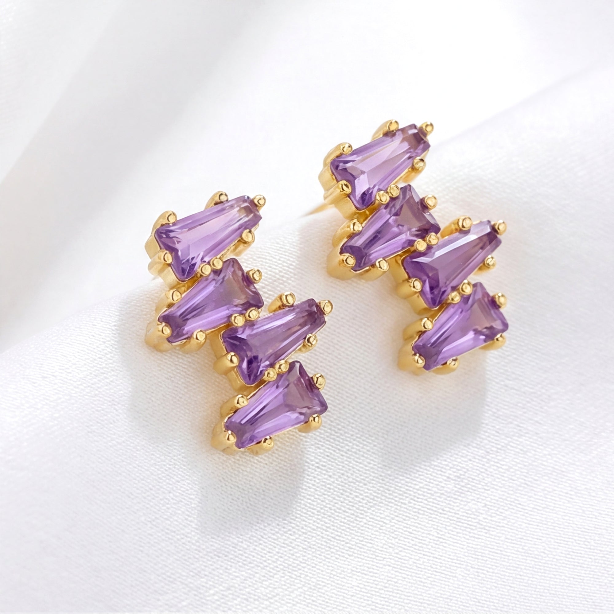 Angled view of Callista cluster stud earrings in 18K gold vermeil with tapered baguette simulated amethyst.