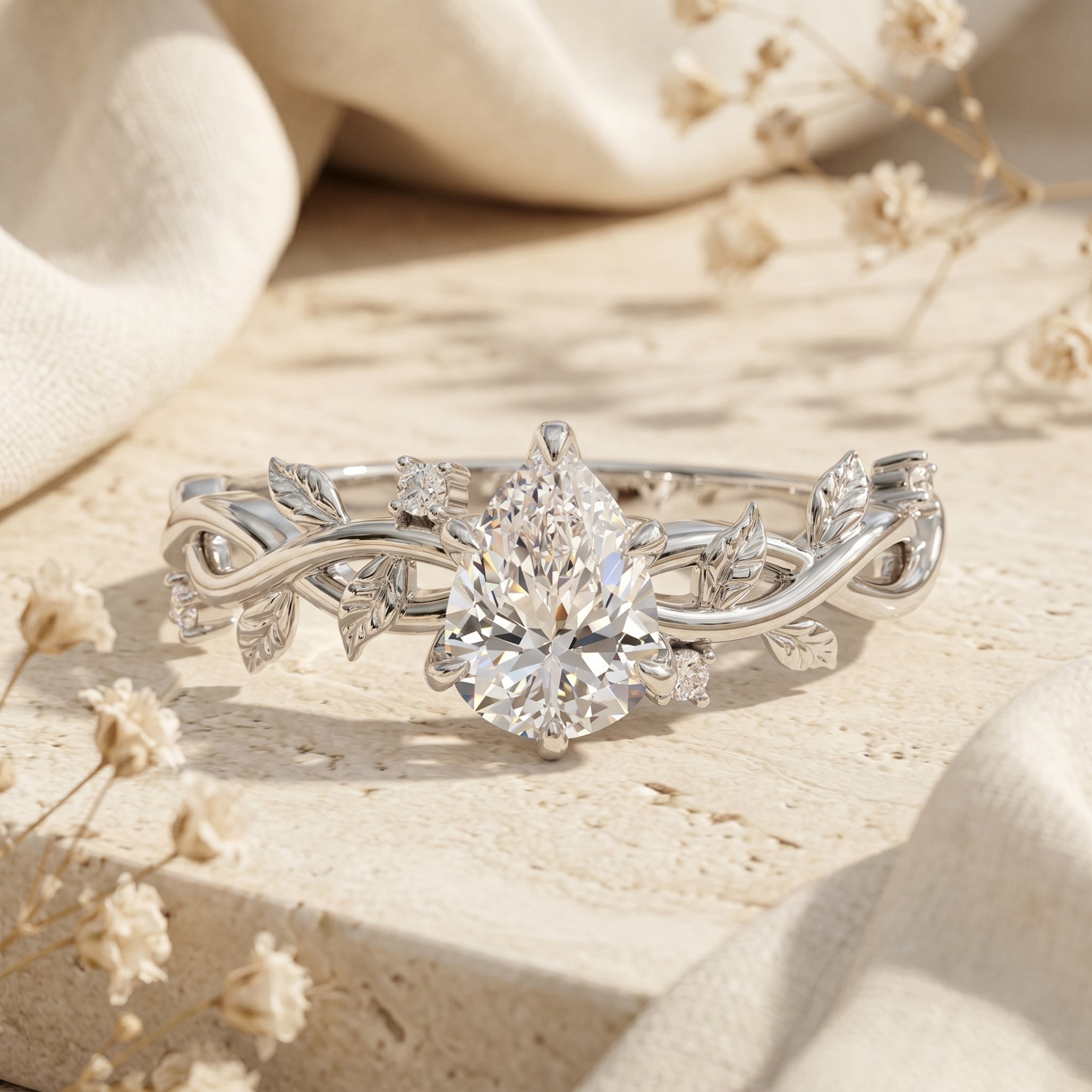 Pear cut moissanite silver ring with vine band on a stone lifestyle background.