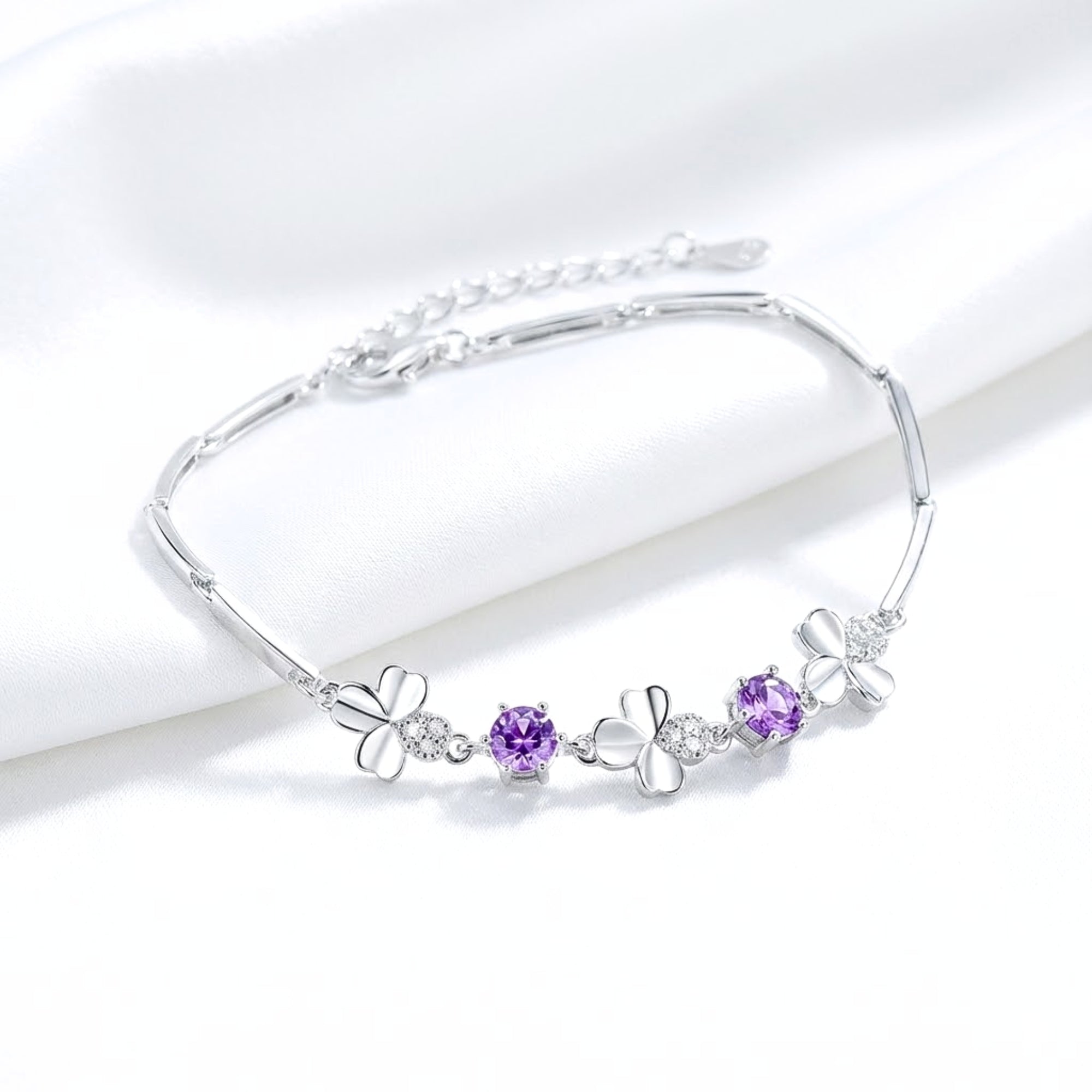 Sterling silver Amoret bracelet with round-cut deep purple simulated amethyst and clovers on white silk with extender.