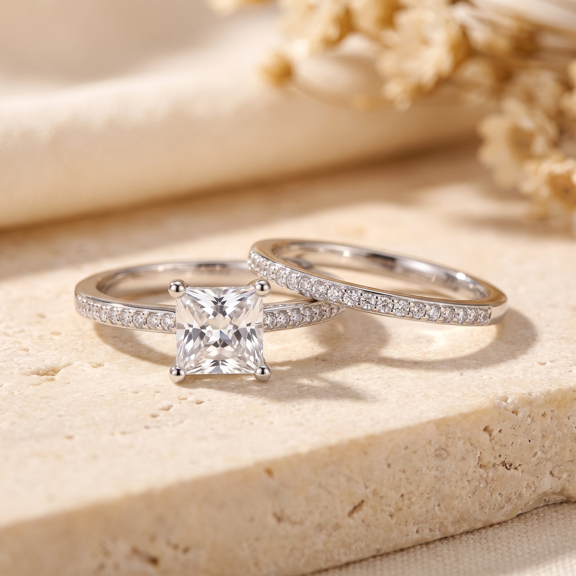 Alaricia sterling silver ring set with square-cut simulated diamond and pavé band on a stone surface.