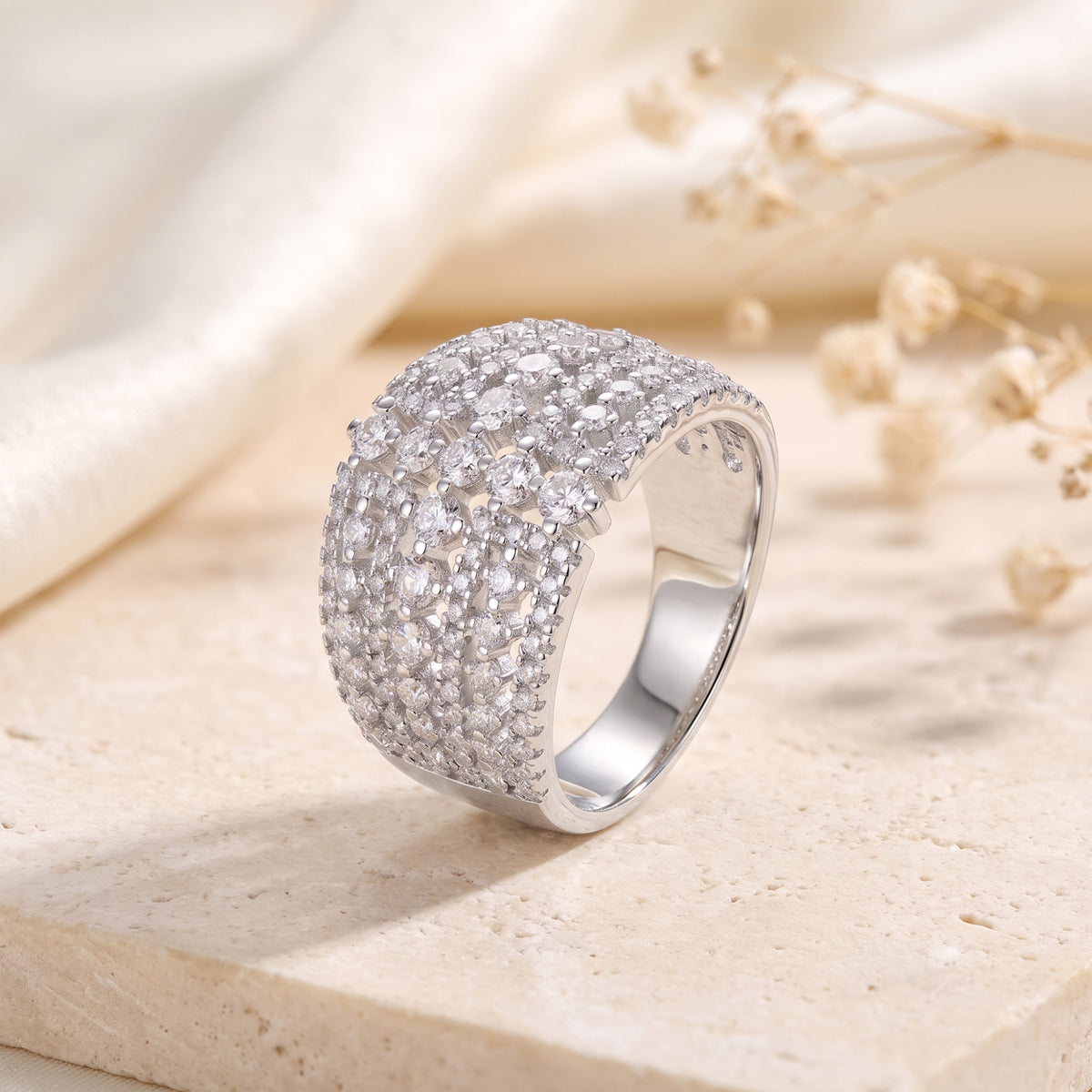 Wide silver ring with an intricate multi-row lattice set with round clear stones, displayed upright.