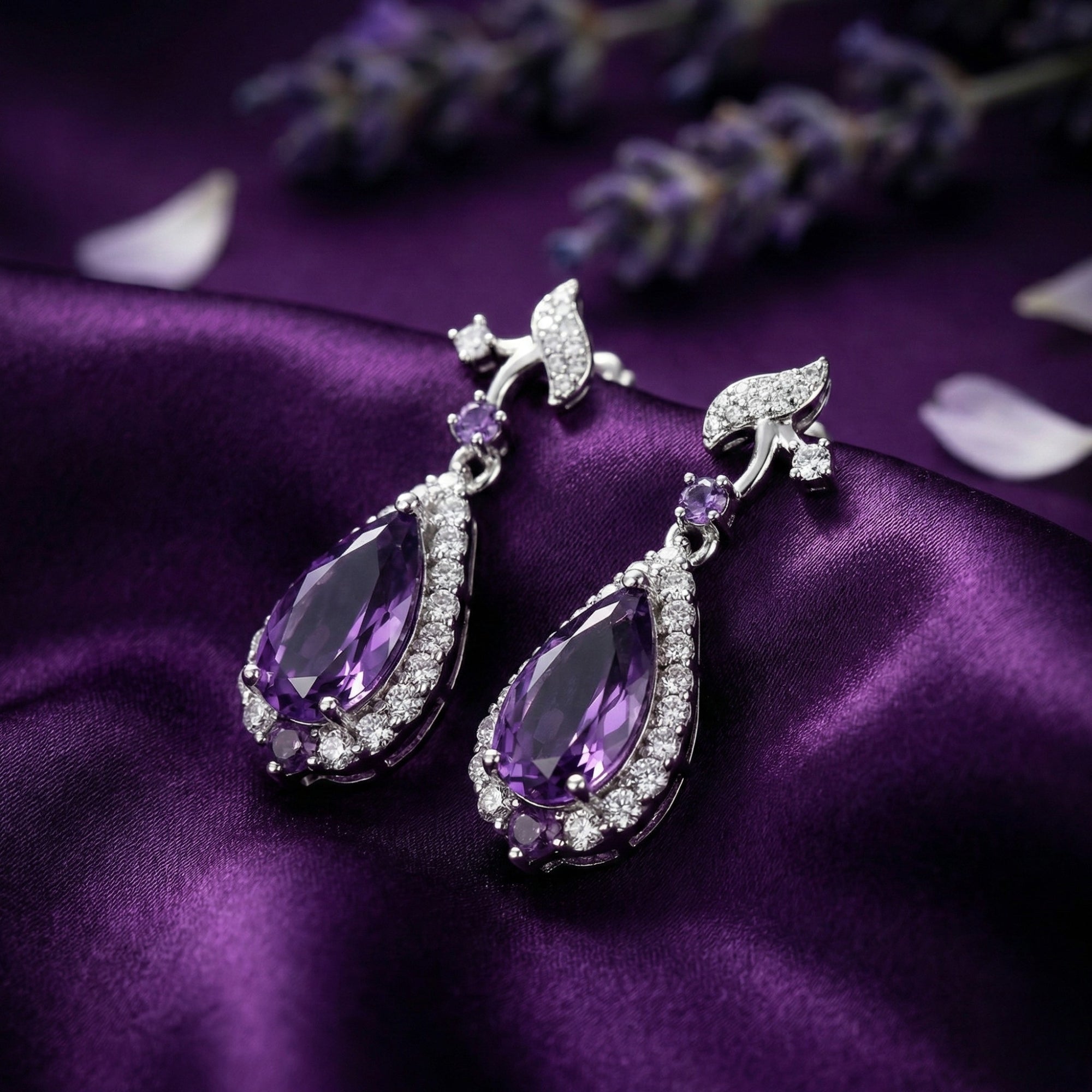Sterling silver pear cut amethyst drop earrings styled on purple silk with lavender sprigs.