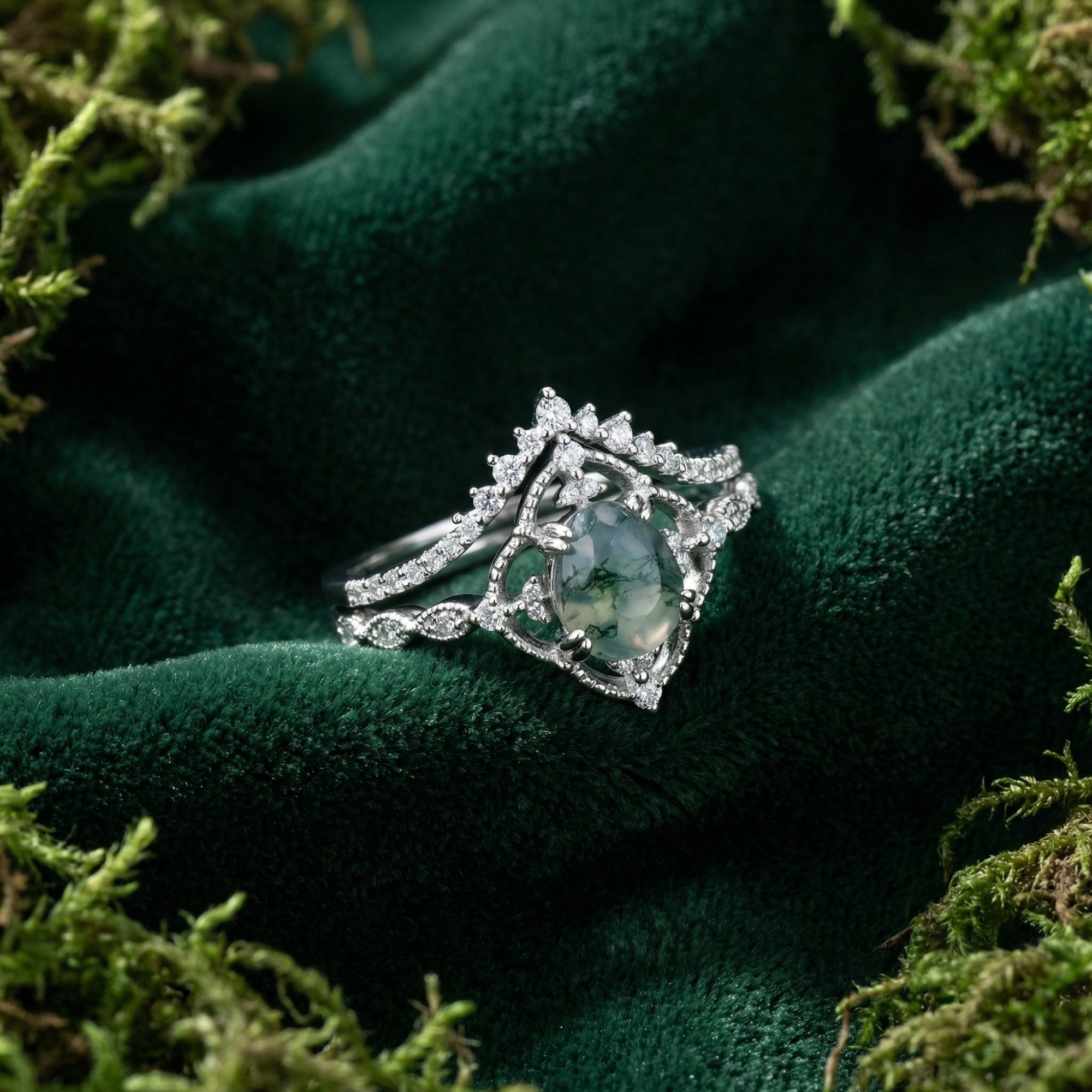 Oval cut moss agate ring set in S925 sterling silver on green velvet with natural moss accents.