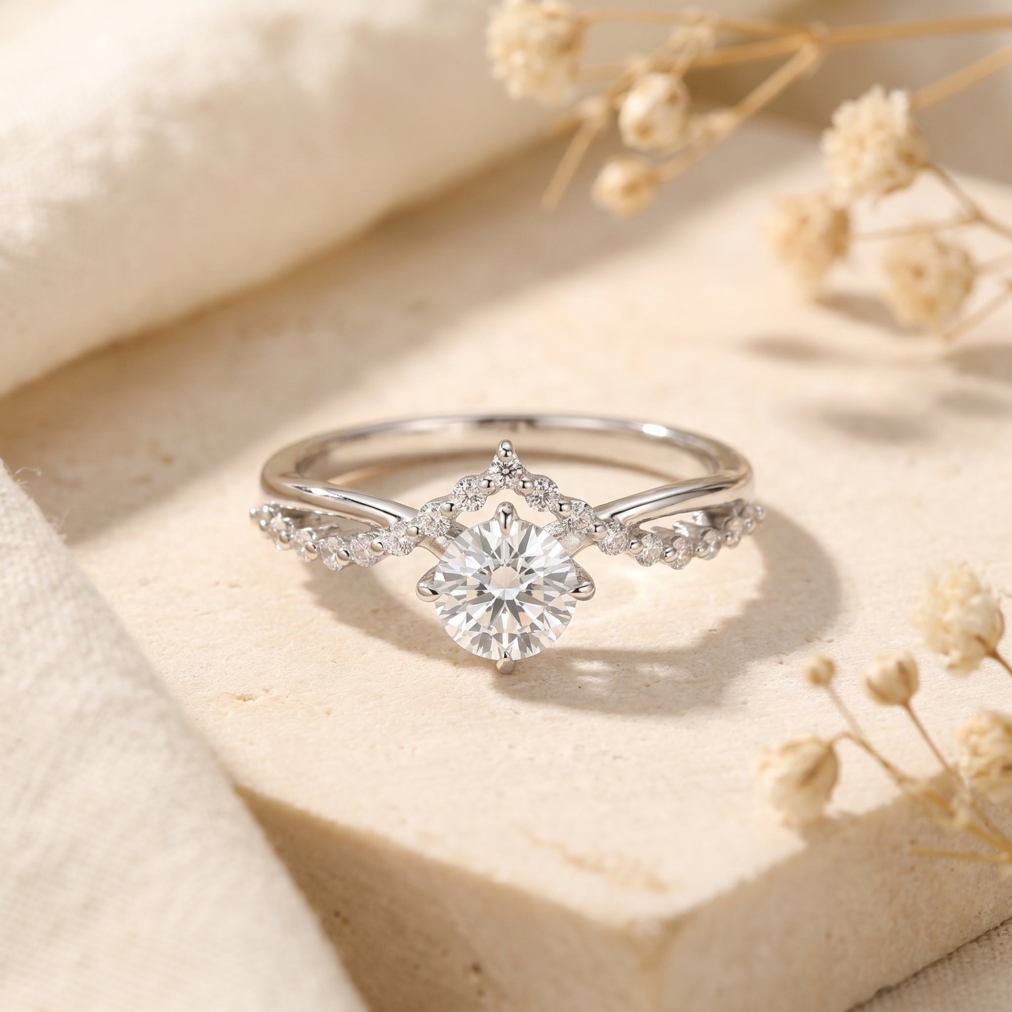 Silver Caladienne crown promise ring with a 1CT round moissanite center stone on a neutral stone background.