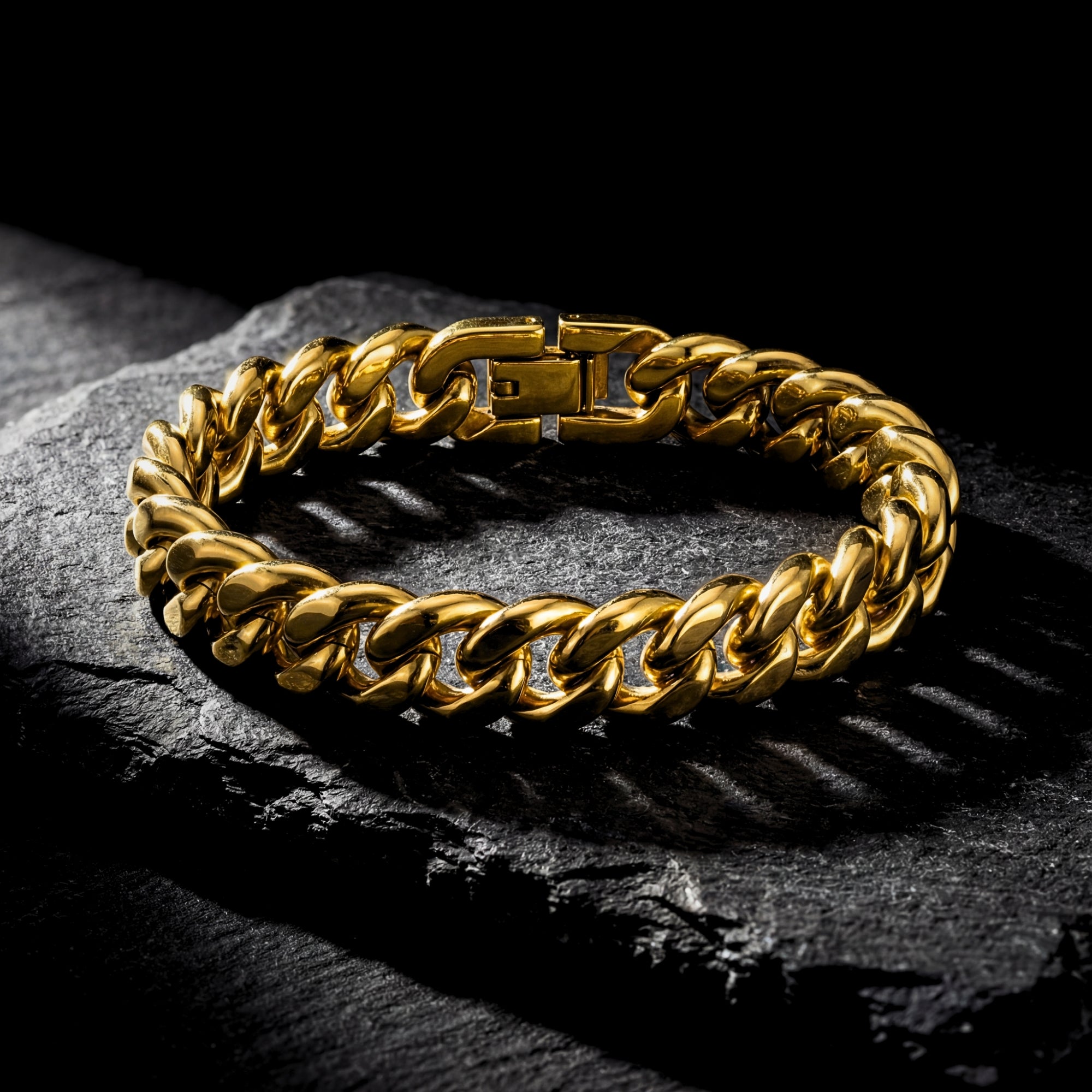 Angled view of a gold 10mm Cuban link stainless steel bracelet on a dark textured stone surface.