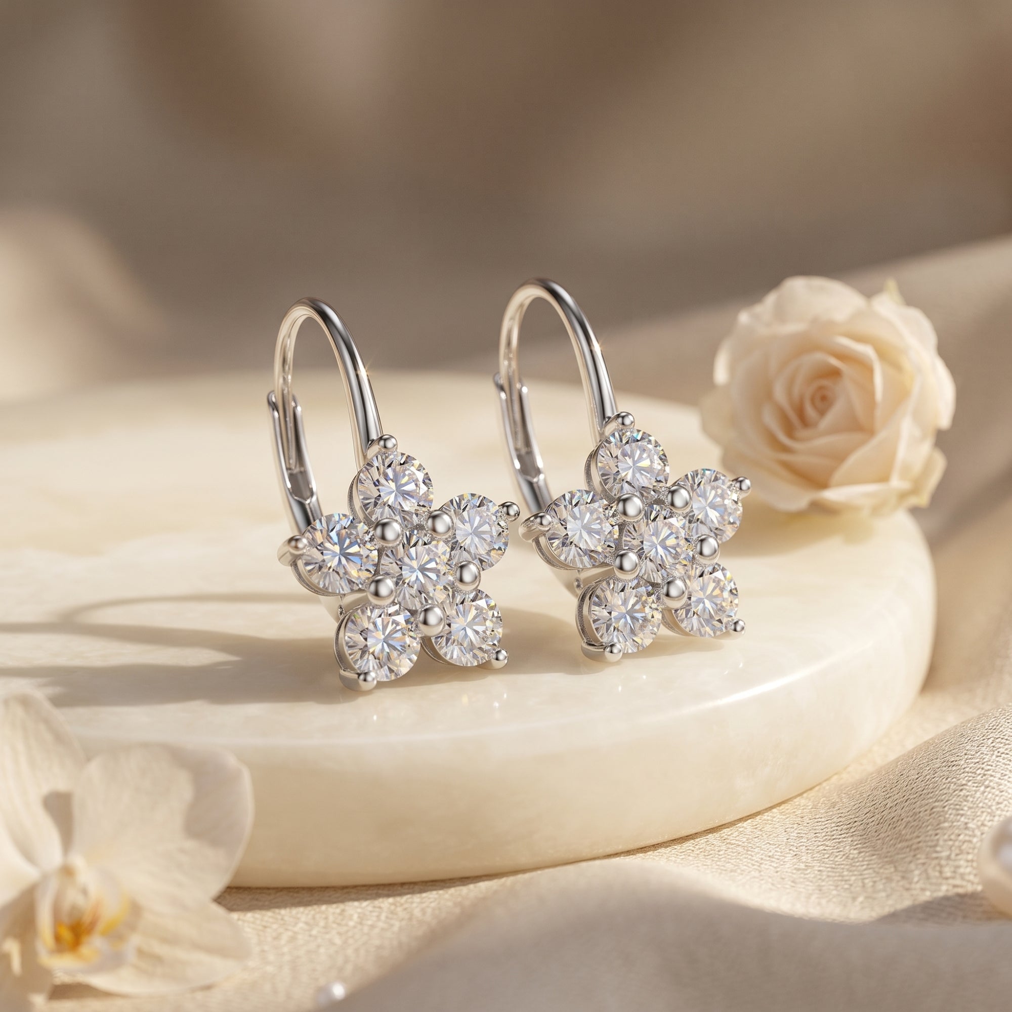 Silver floral moissanite drop earrings on marble with white roses.