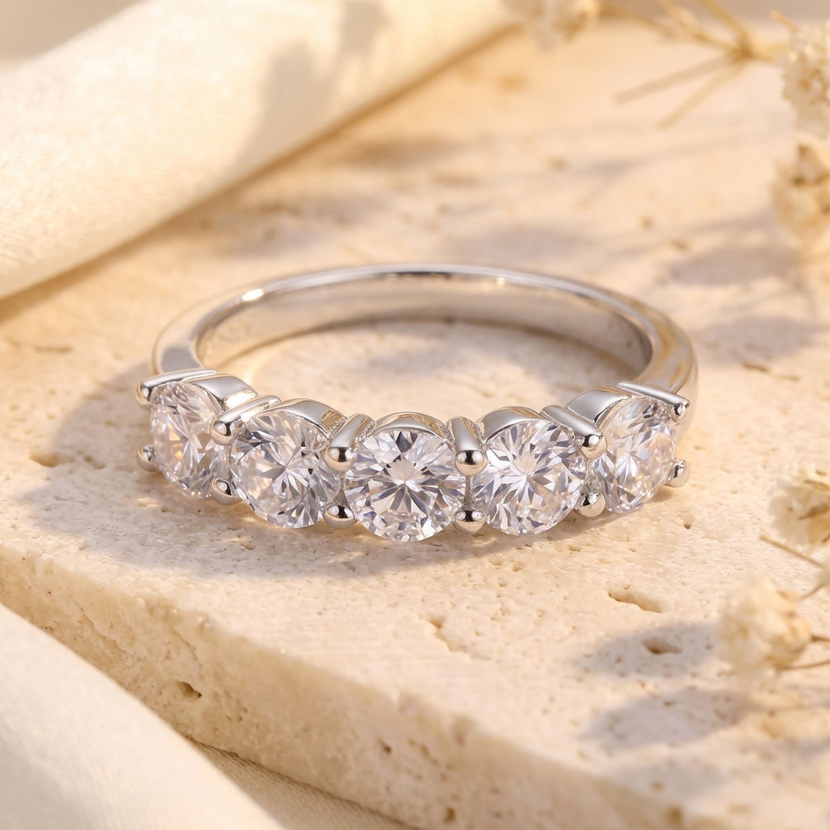 Front close-up view of a silver ring set with five round-cut clear stones in shared prongs.