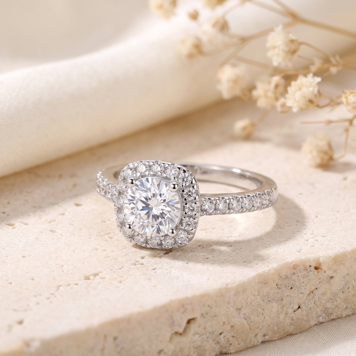 Front view of the silver cushion halo ring with a round center stone on a stone tile.