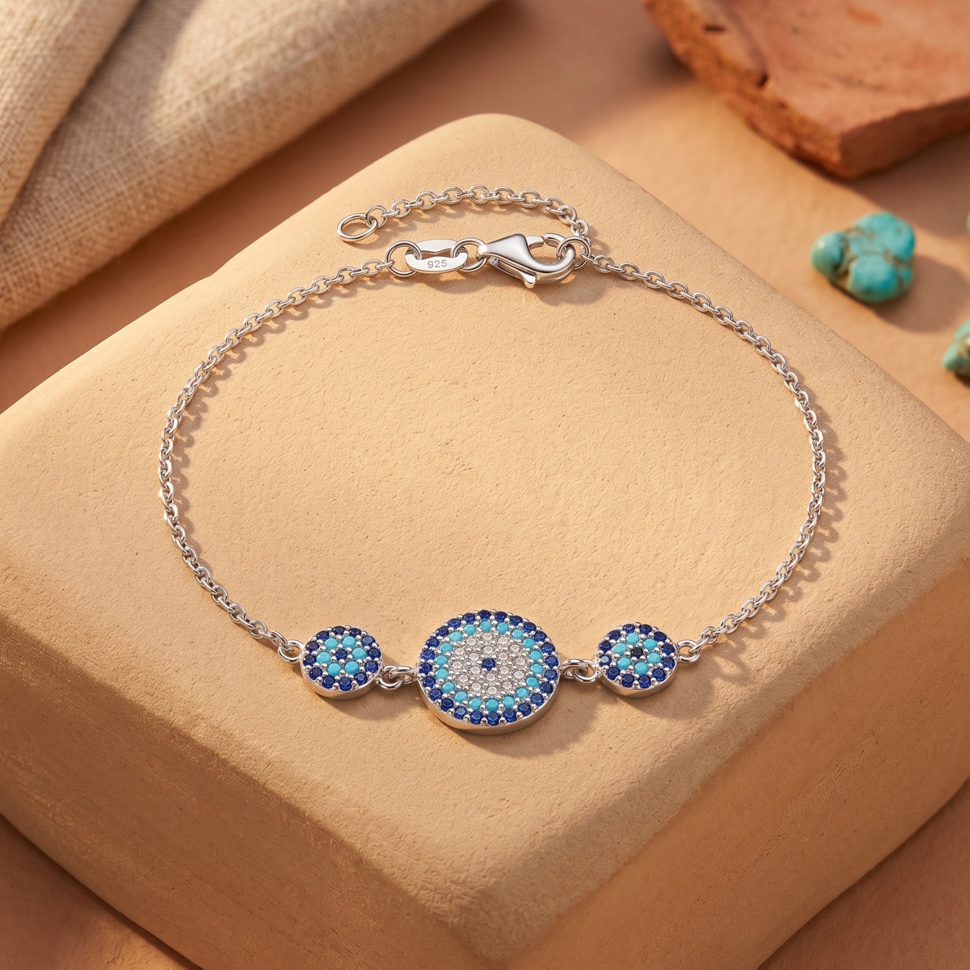Paloma turquoise silver bracelet with three circular pavé stations and lobster clasp on a desert stone block.