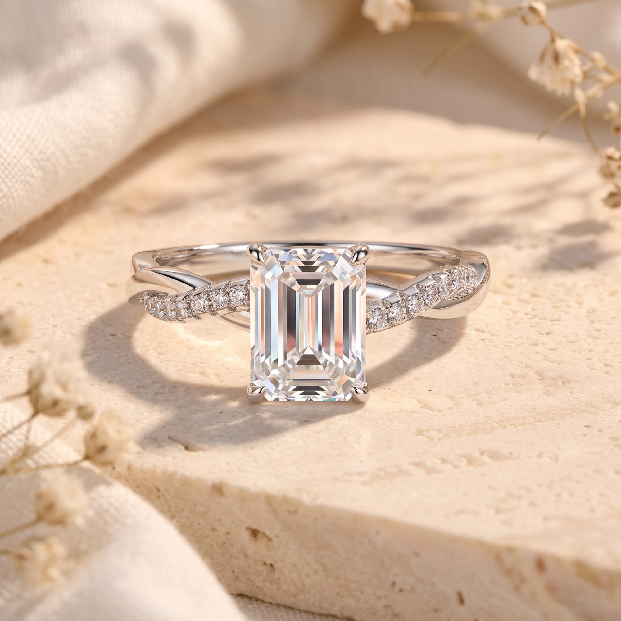 Emerald cut CZ promise ring in sterling silver with a twisted pavé band on a stone surface.