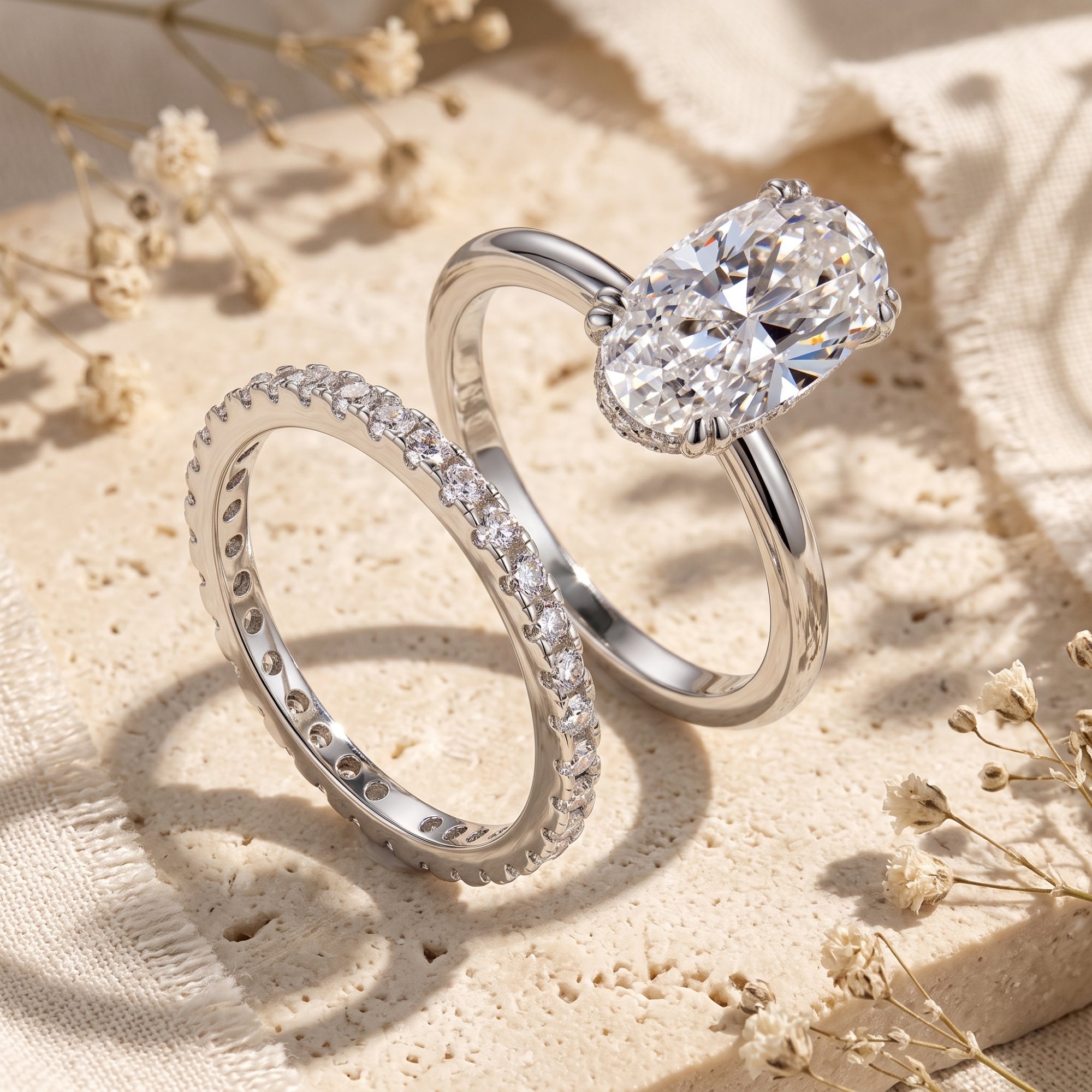 Oval-cut simulated diamond silver ring set on stone with dried flowers.