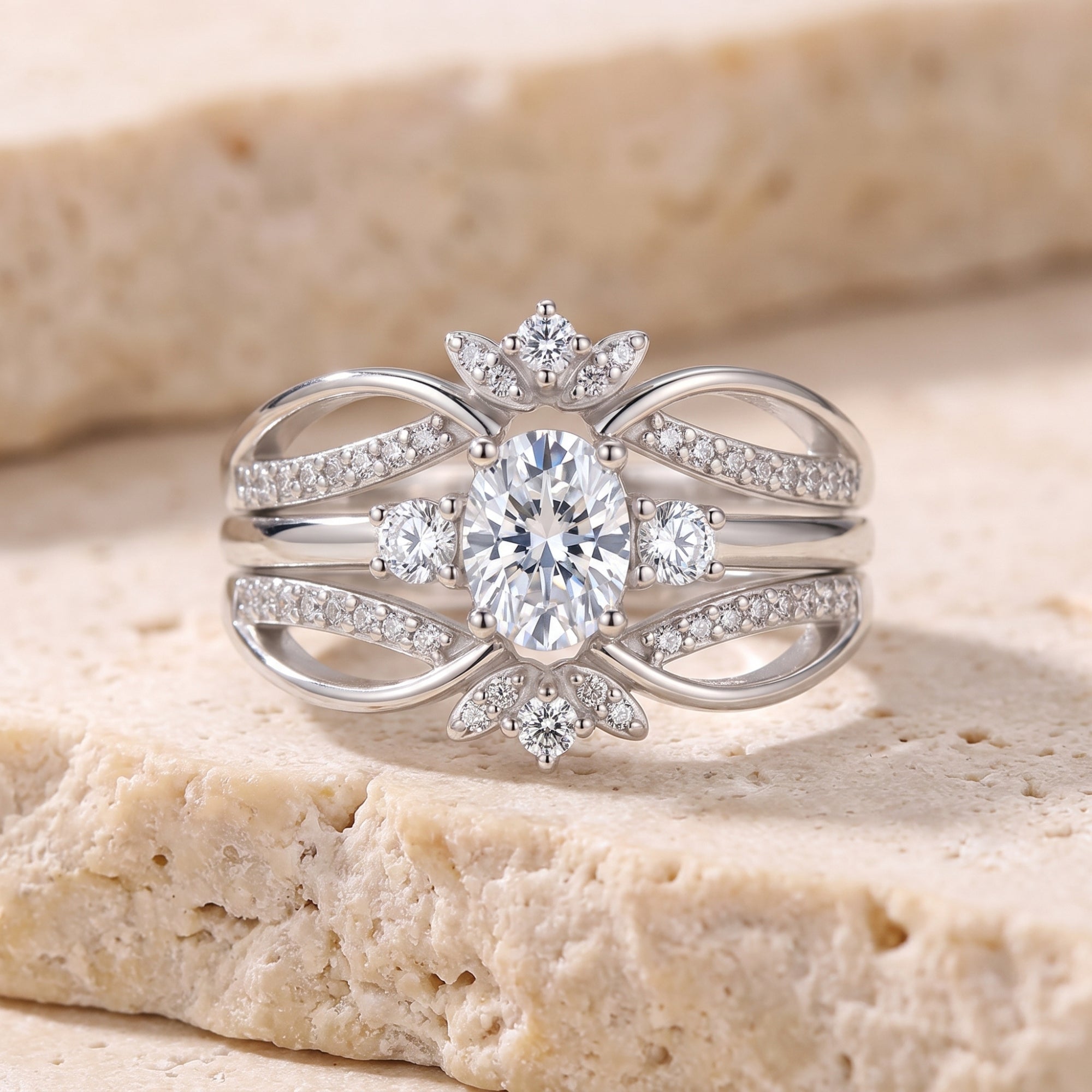 Oval-cut simulated diamond ring in sterling silver with multi-layered bands on a stone background.