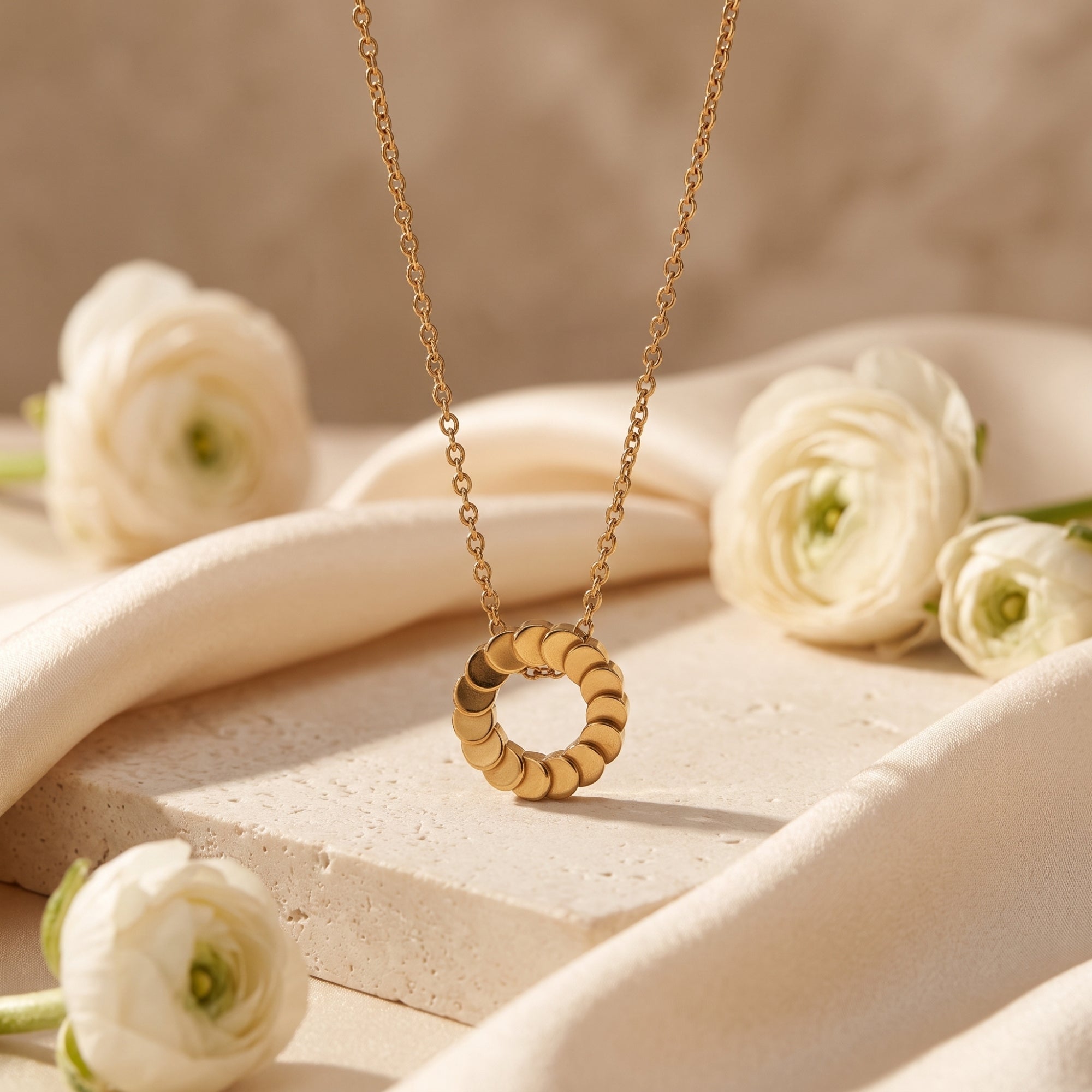 18K gold plated Freya necklace with disk pendant styled with white flowers and fabric.
