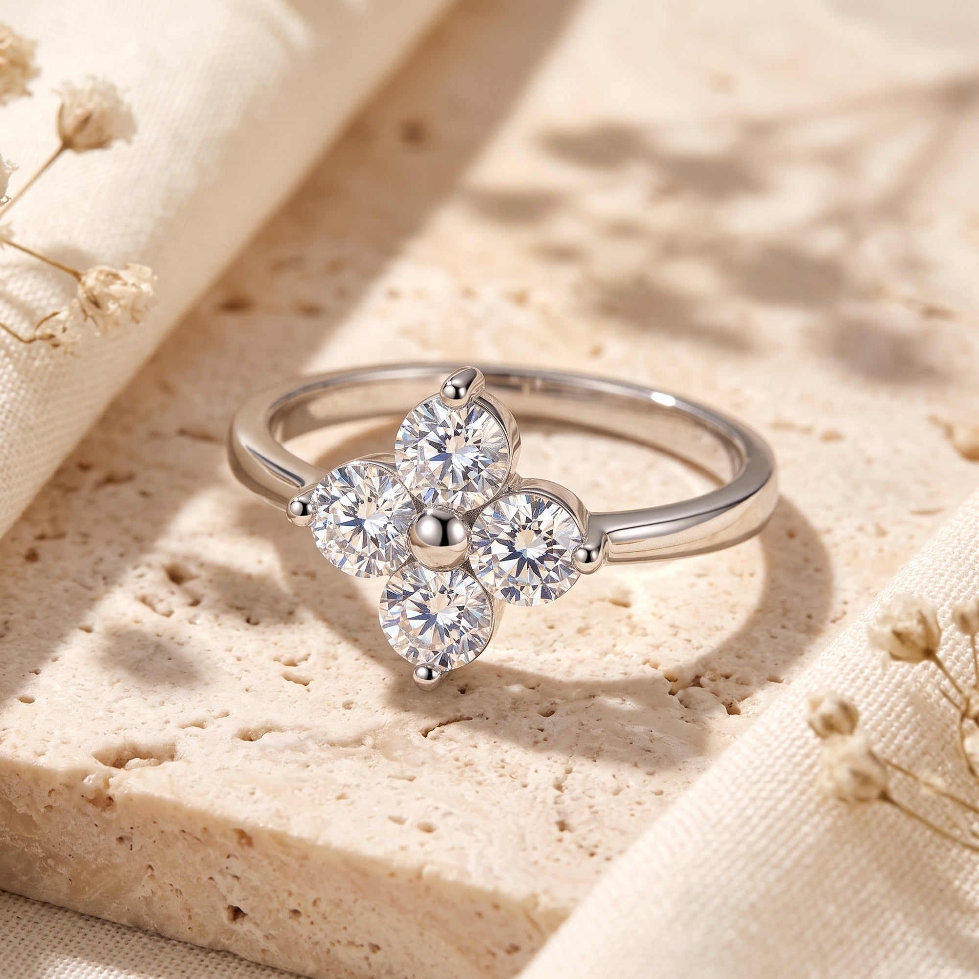 Silver clover promise ring with round cubic zirconia stones on a textured stone background.
