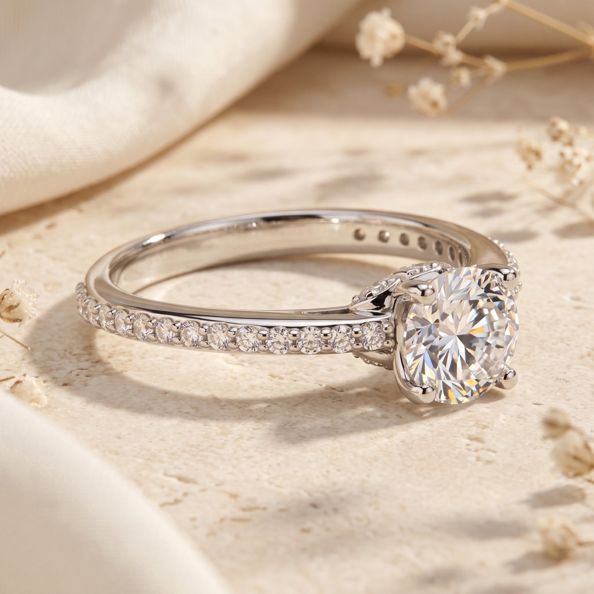 Josephine sterling silver ring with round-cut simulated diamond on a stone surface with flowers.