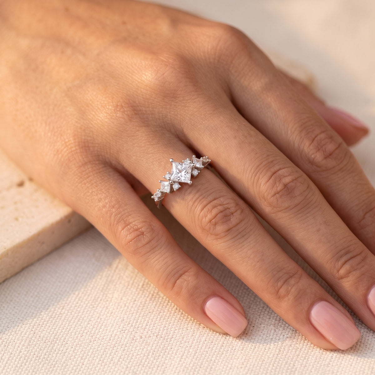 Princess-cut CZ silver promise ring on a woman's hand in natural light.