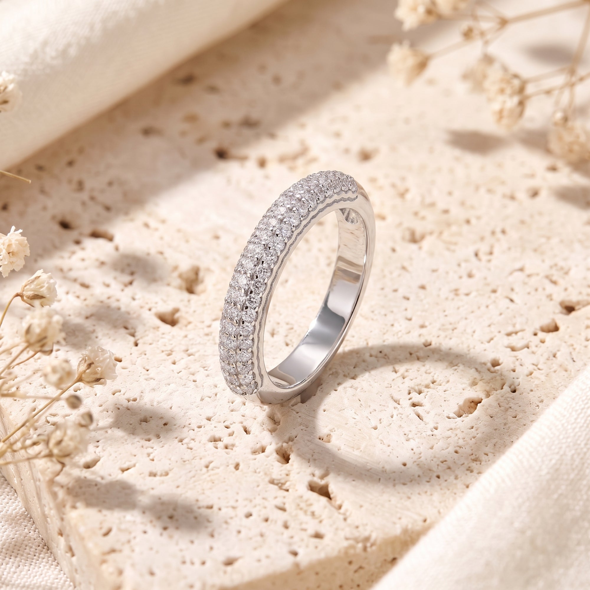Florentina sterling silver ring with three rows of round simulated diamonds on a textured stone surface.