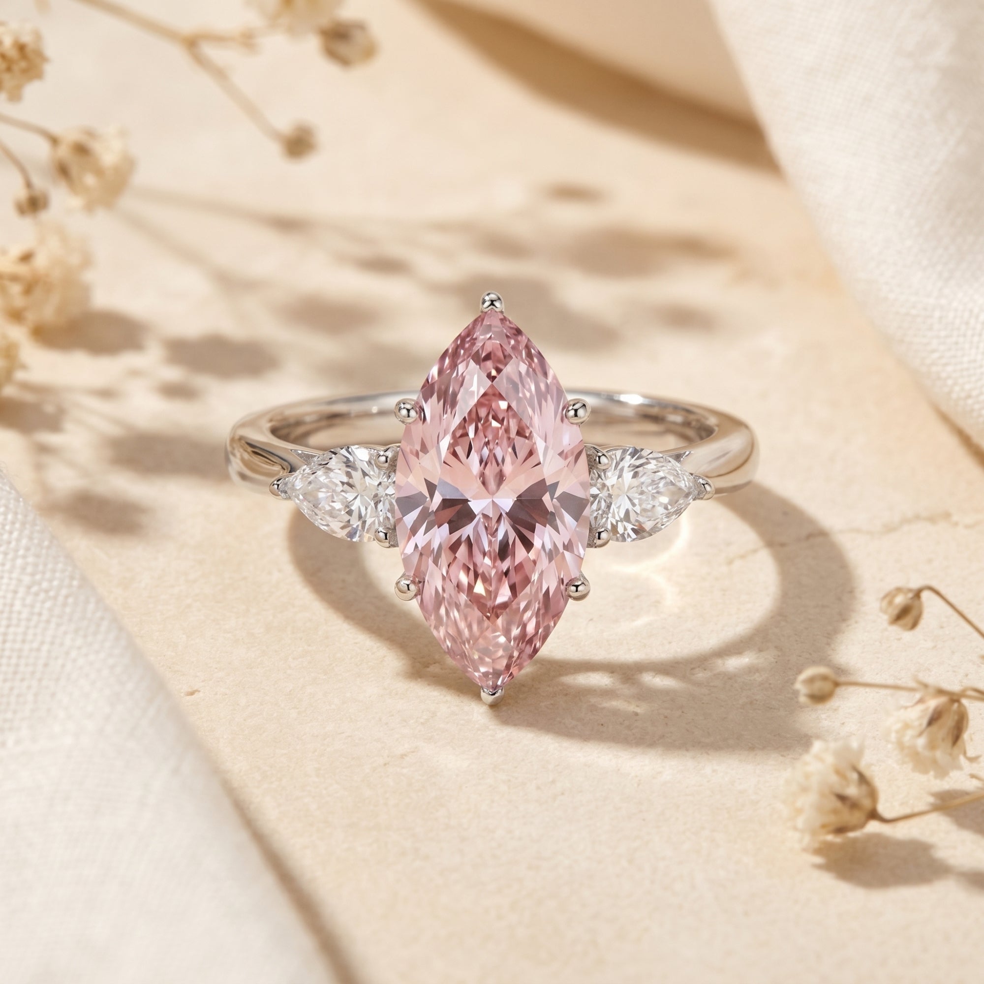 Marquise pink moissanite silver promise ring with pear side stones on a neutral lifestyle background.