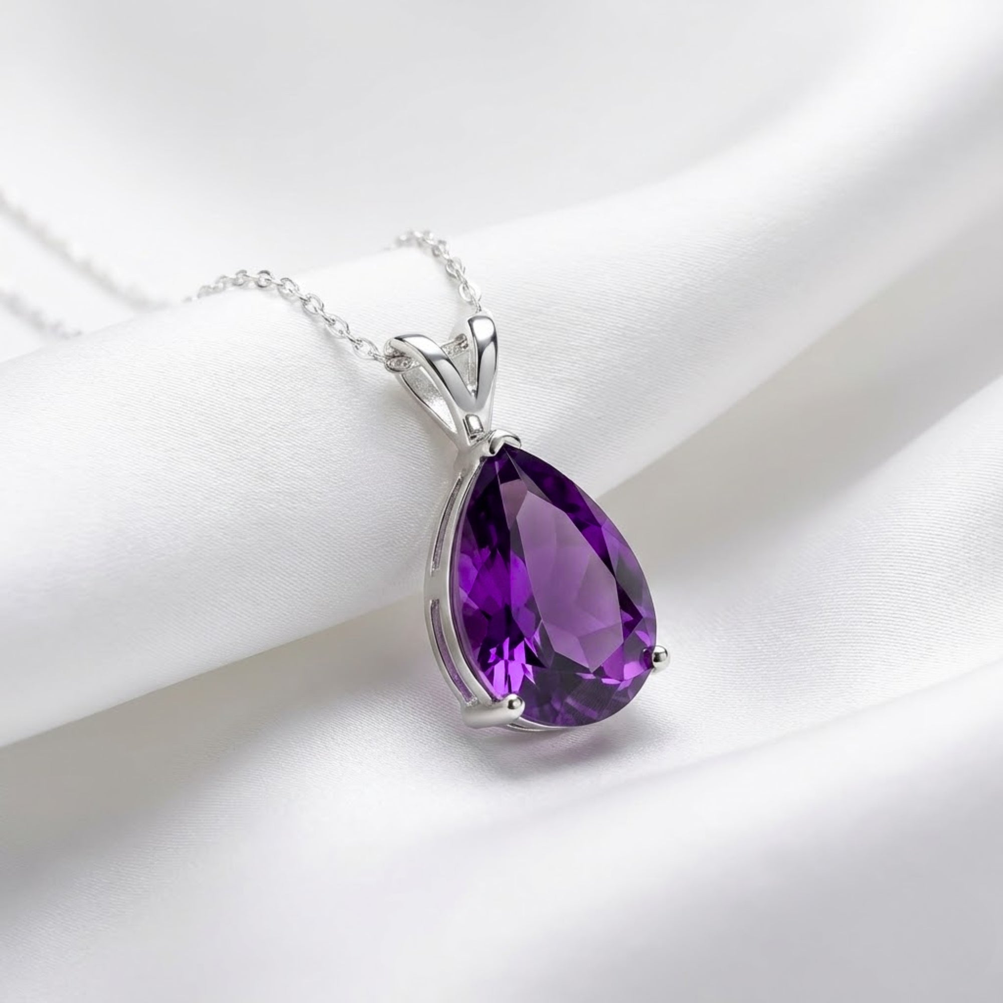 Teardrop purple moissanite pendant in S925 sterling silver on a white silk background.