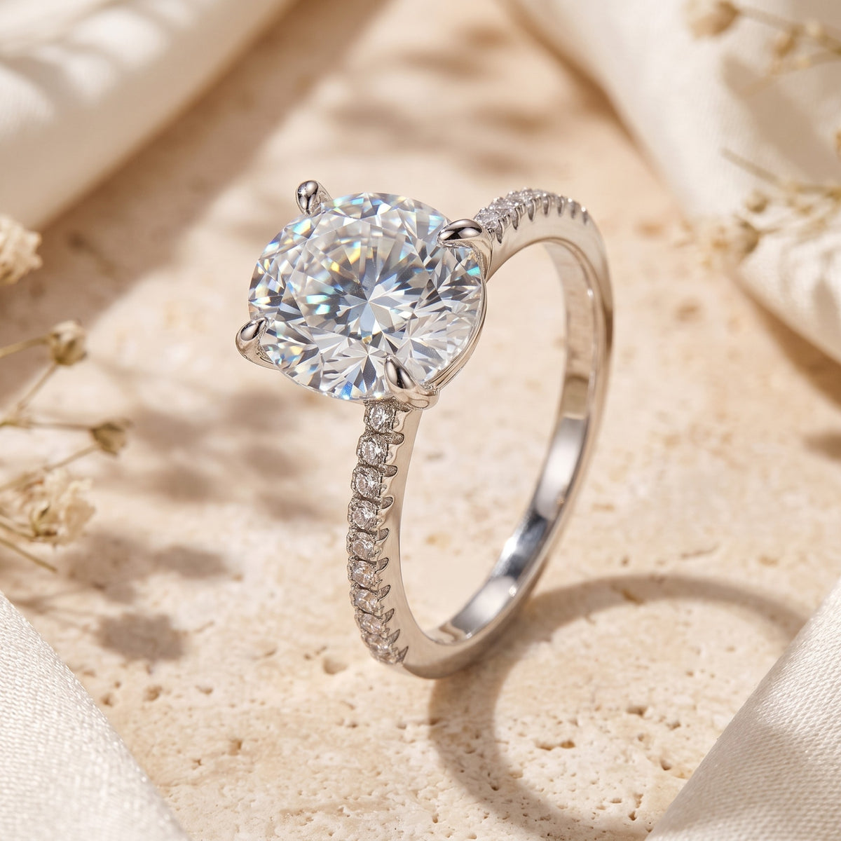Angled close-up of a silver ring with a large oval center stone and pavé band on a textured stone surface.