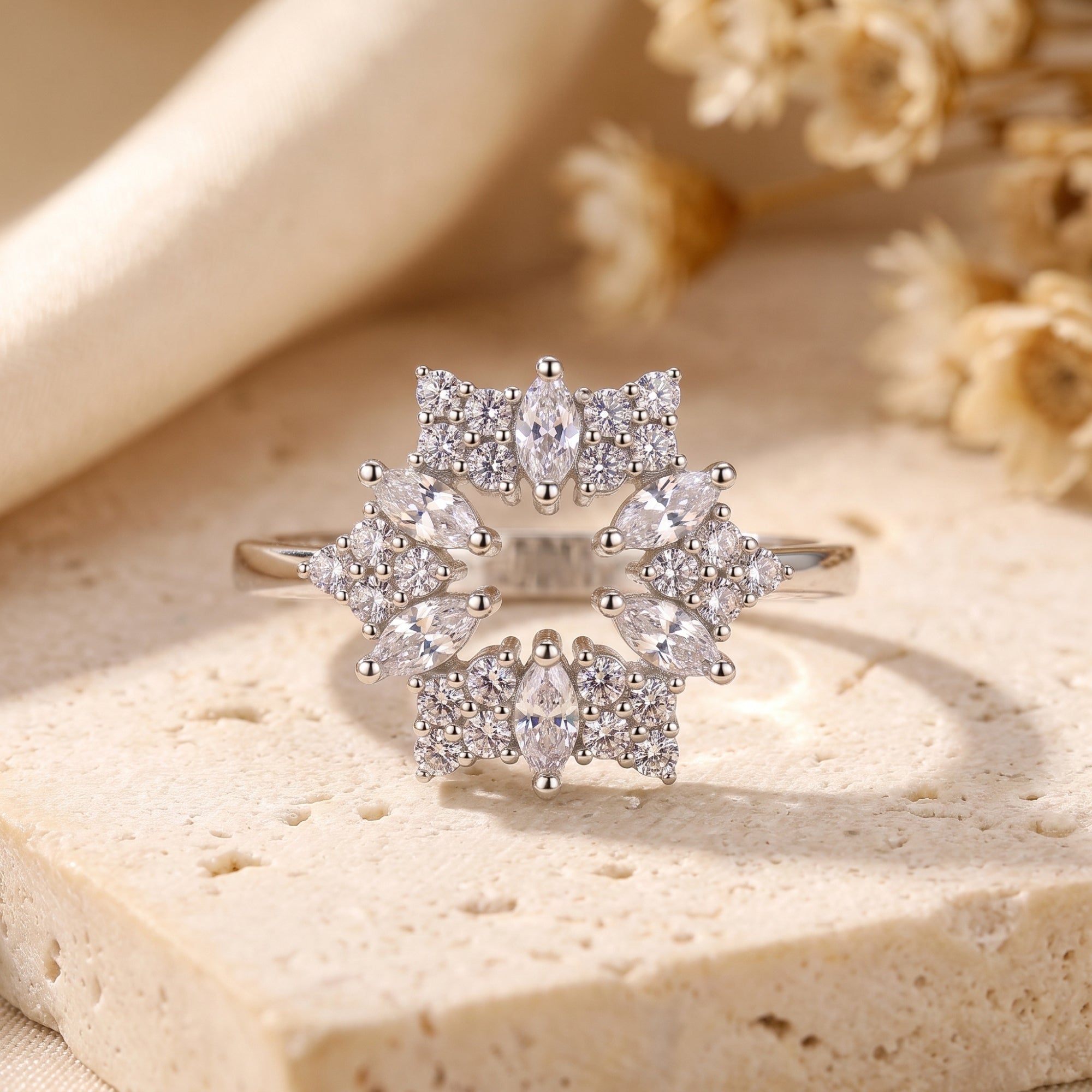 Front view of the Stellaire S925 sterling silver starburst ring with marquise stones on a stone surface.