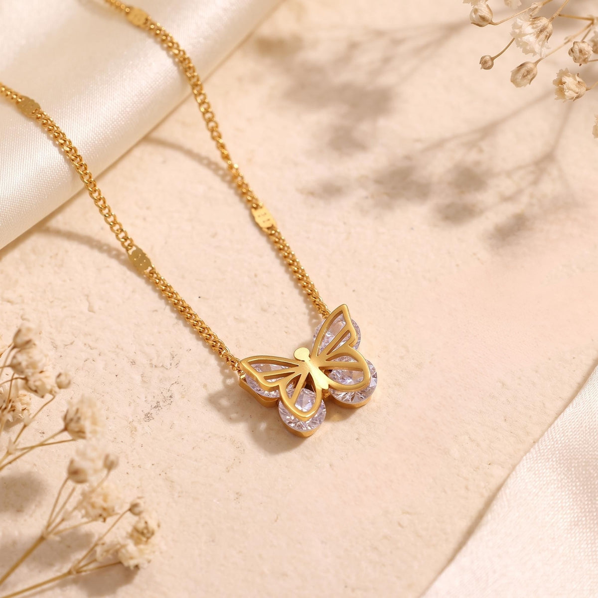 Close-up of the openwork butterfly pendant with clear cubic zirconia wings on a gold-tone chain.