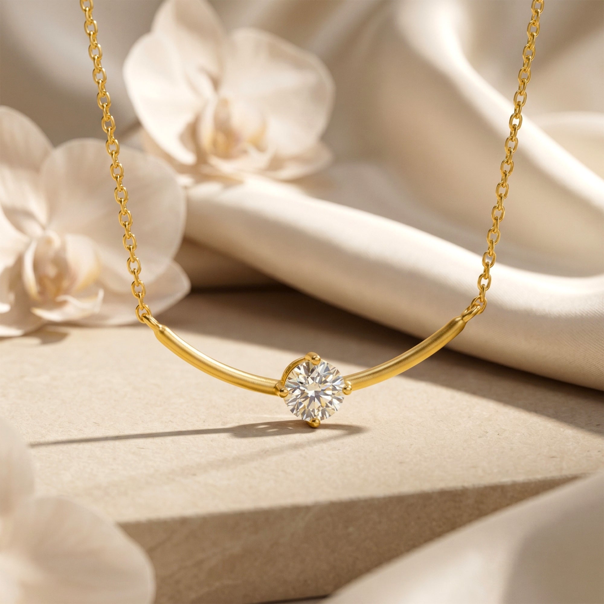 Gold Elionara necklace with round moissanite on a curved bar, styled with white orchids and silk.