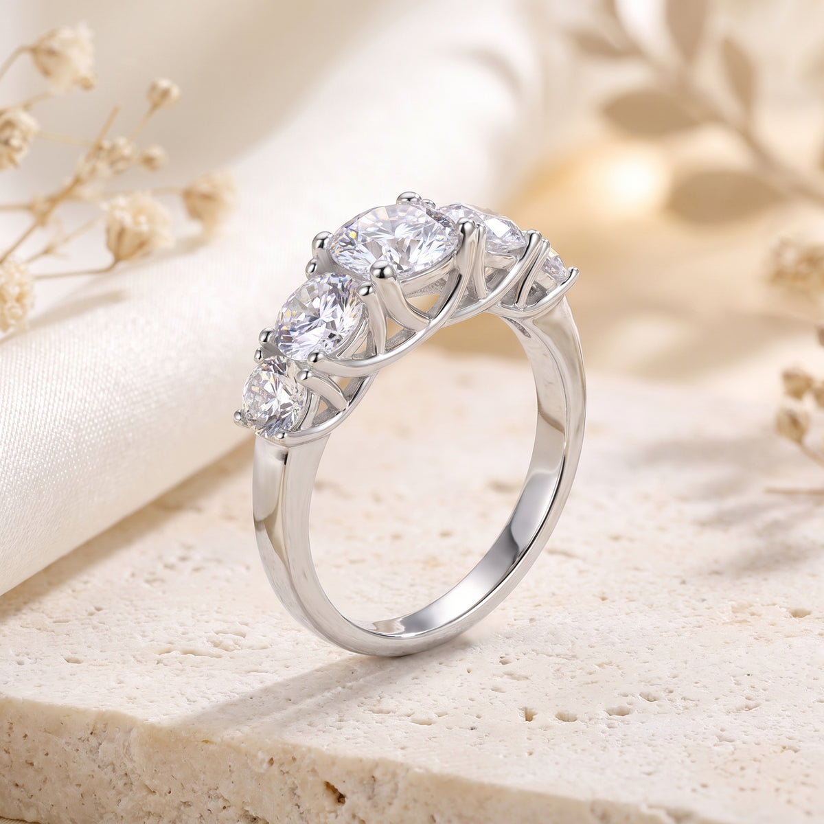 Angled close-up of the silver ring with five graduated round clear stones in basket settings.