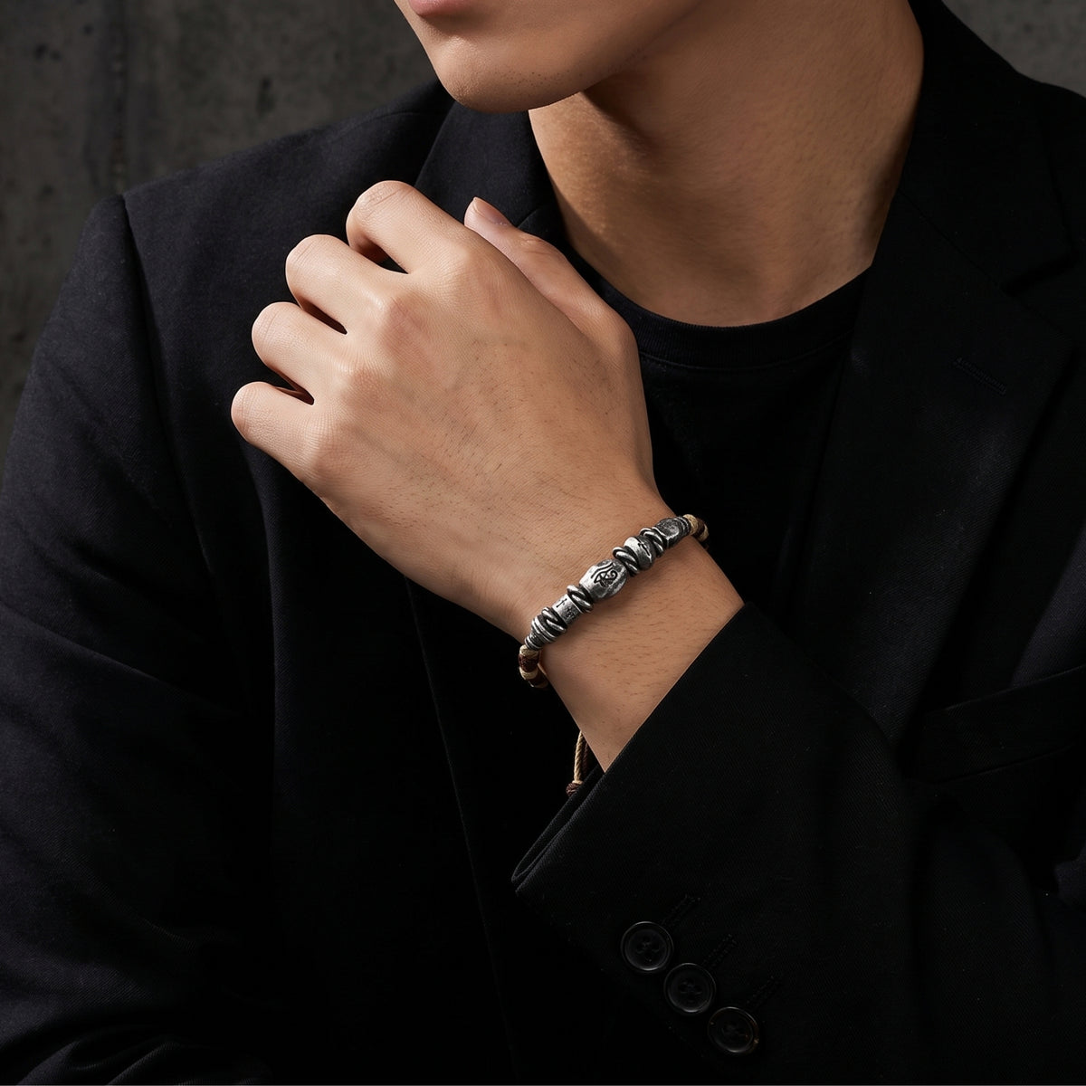 Man wearing the silver Eye of Horus braided cord bracelet on his wrist with a black blazer.