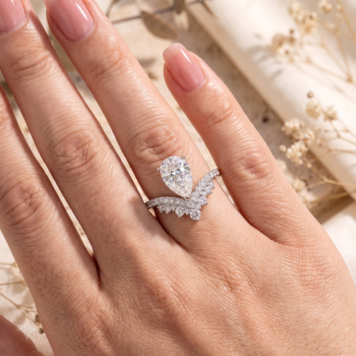 Pear-cut simulated diamond wishbone ring in sterling silver worn on a finger.