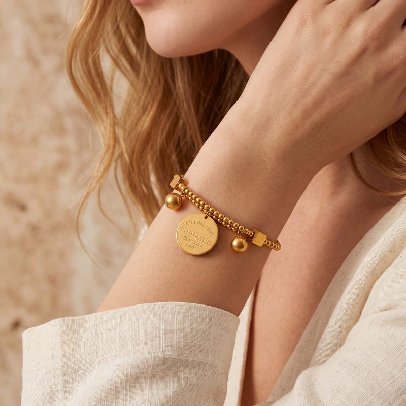 Close-up view of the gold-tone beaded disc bracelet worn on a model's wrist.