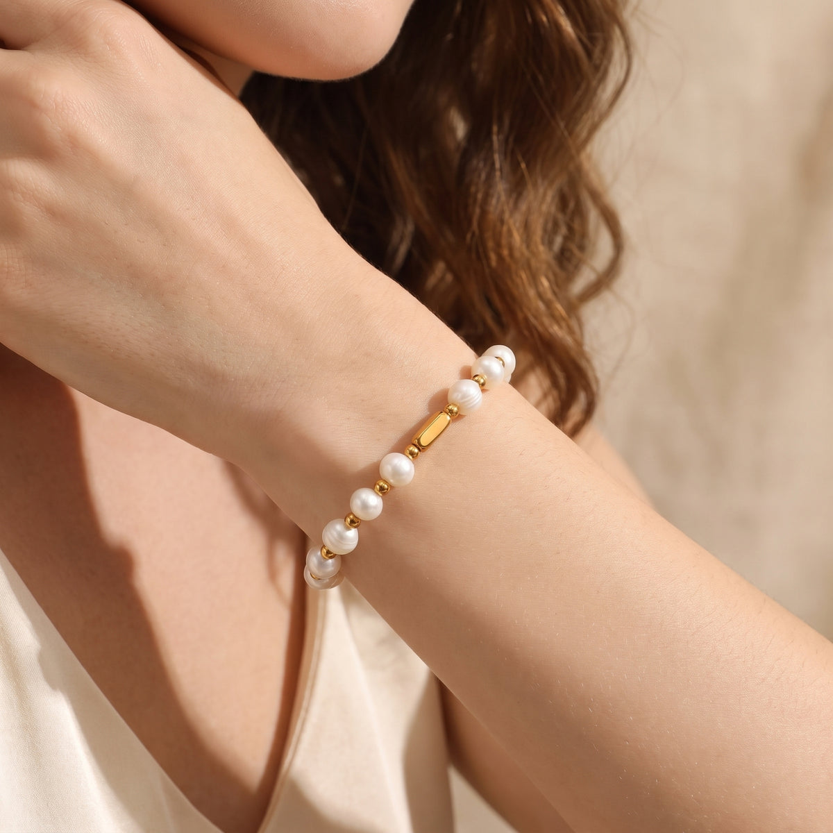 Close-up view of the Pearl Station Bracelet worn around a wrist, showing white pearls and gold-color details.