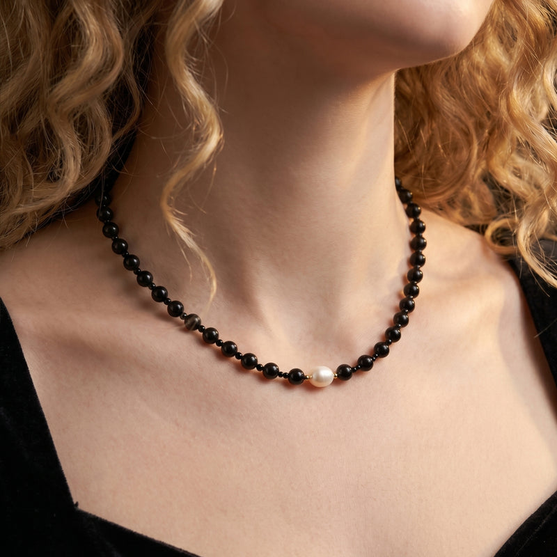 Model wearing the black onyx and white pearl necklace with 18K gold plated beads.